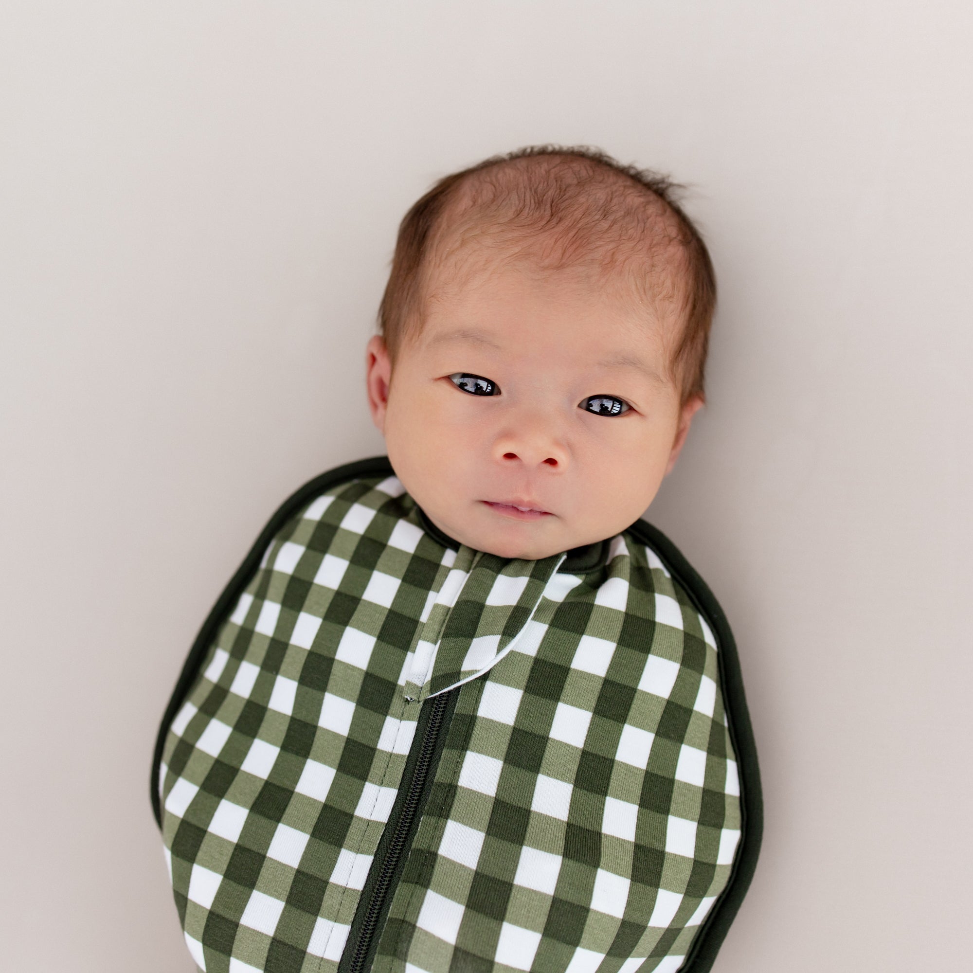 Close up on baby's face and top portion of the Swaddle Bag in Gingham Fir 0.5