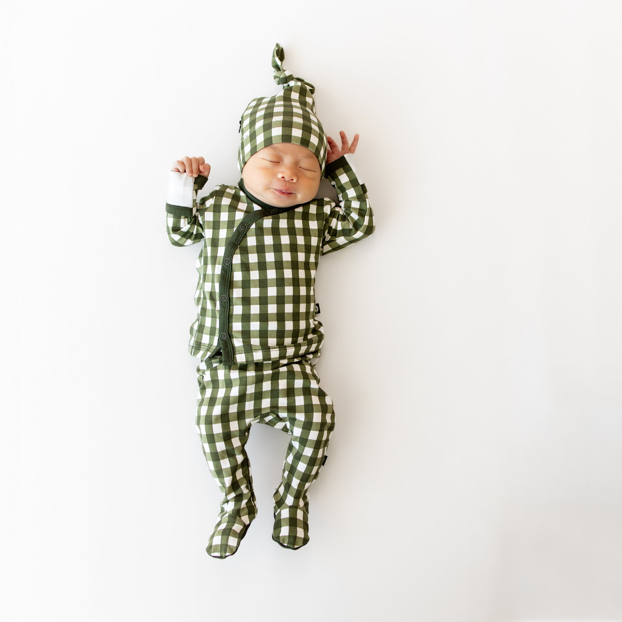 Baby in green and white checkered outfit on a white background