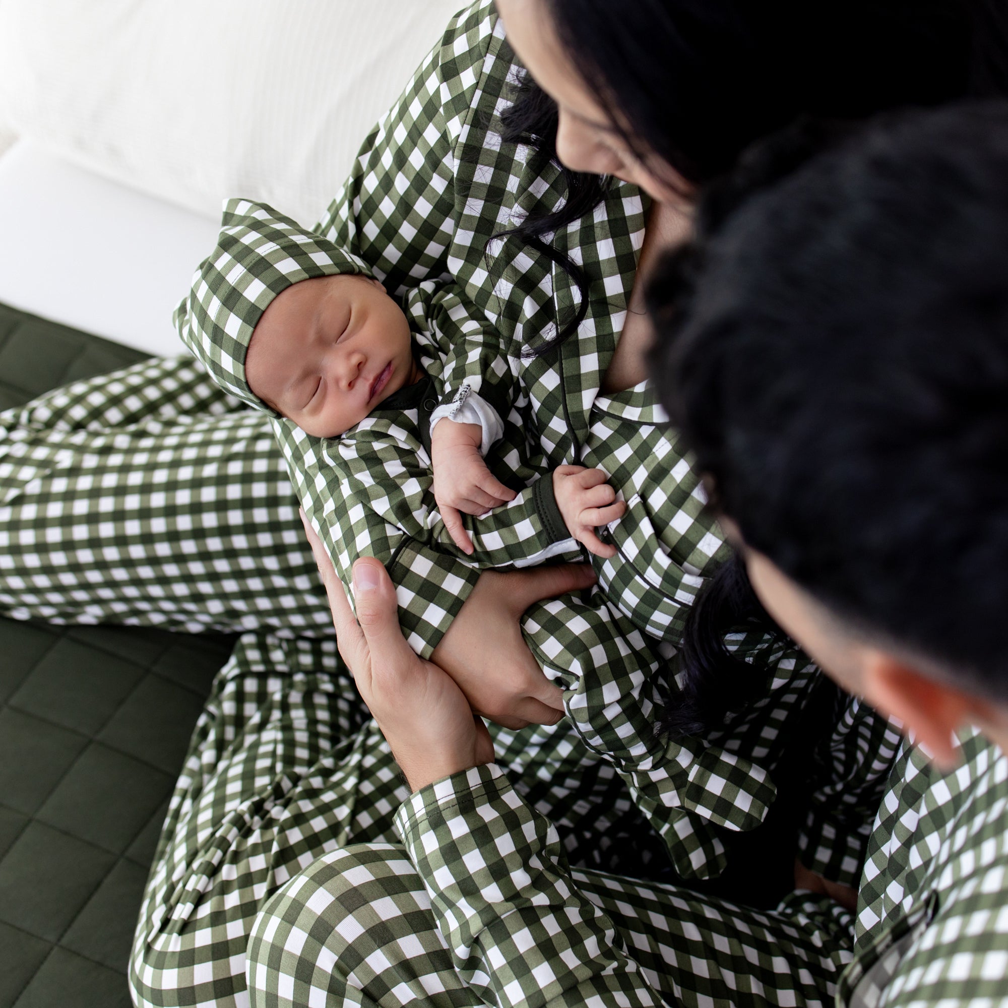 Family of three sitting on a bed all matching in Gingham Fir