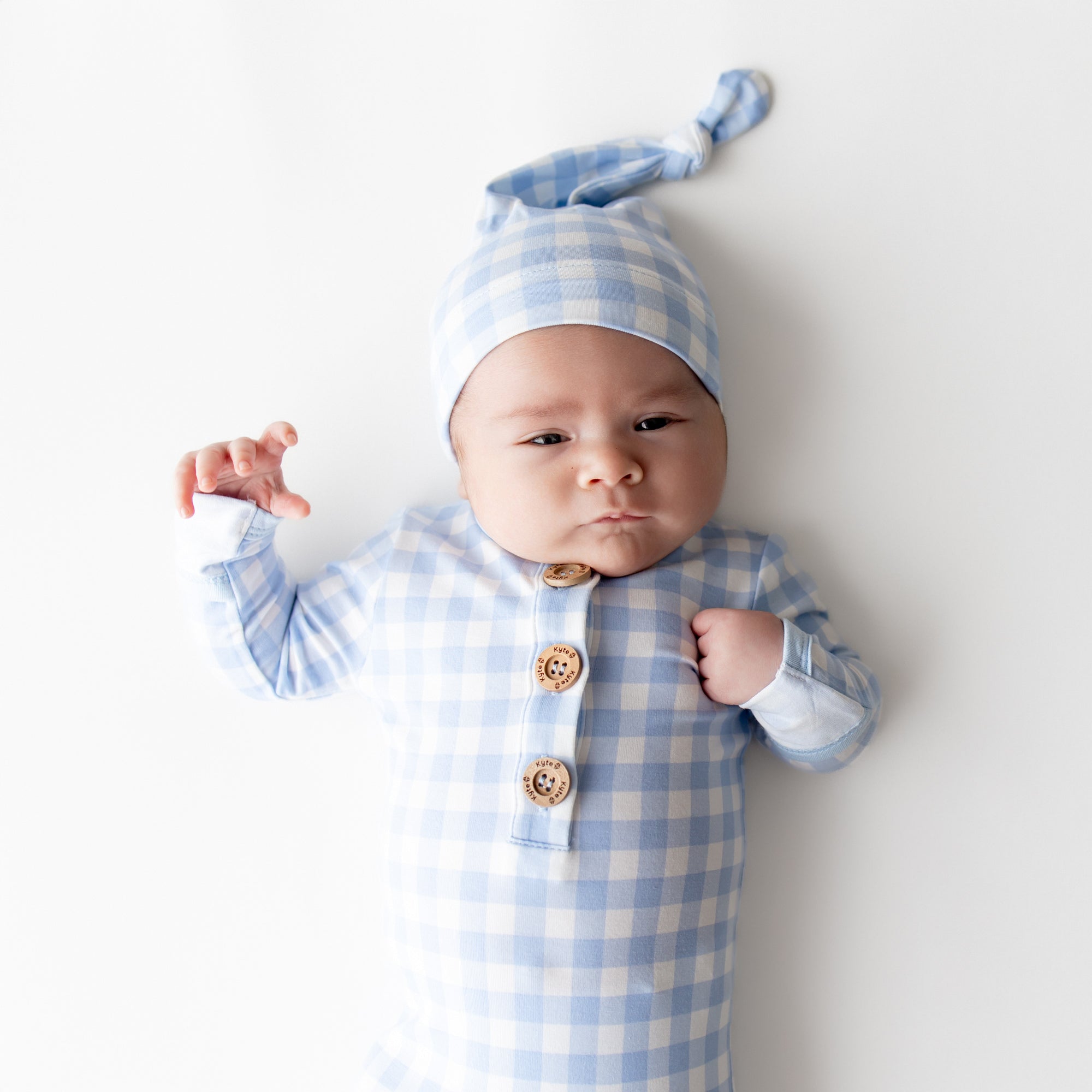 Close up of newborn wearing the Knotted Gown with Hat Set in Gingham Breeze