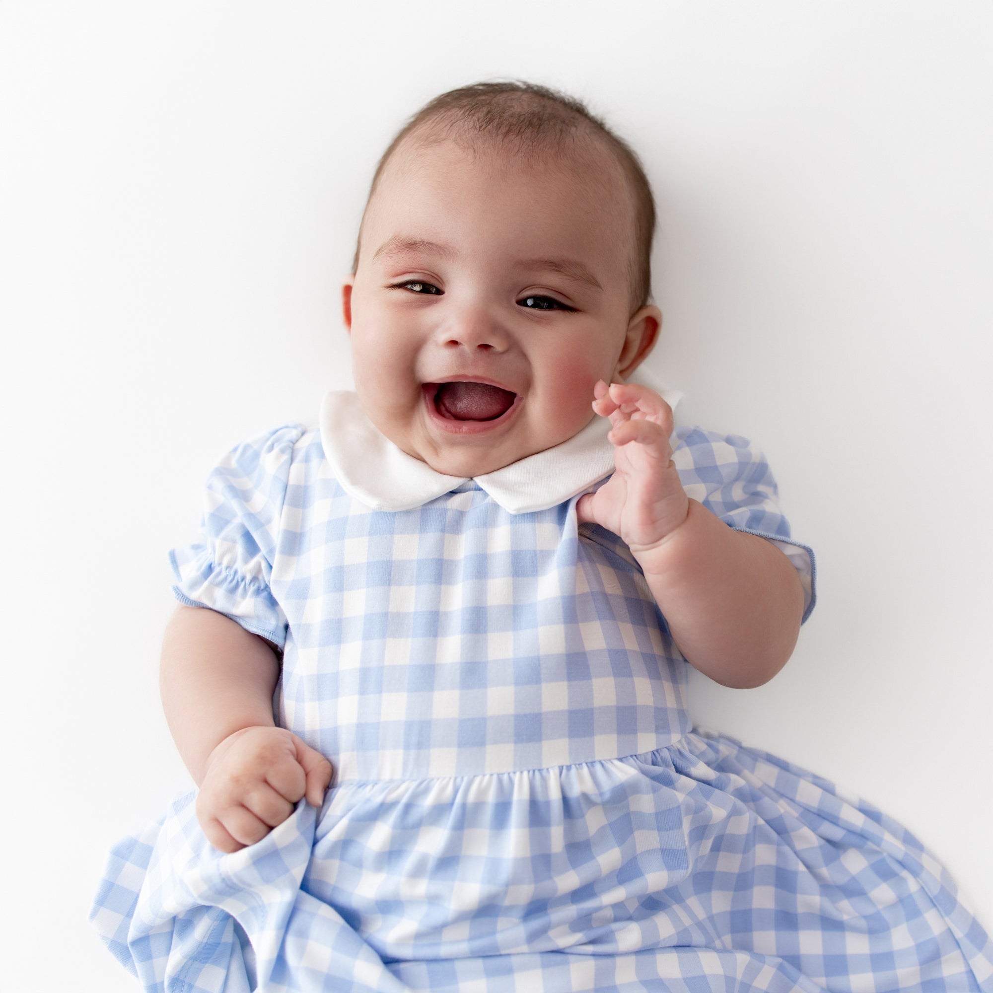 Close up of the Peter Pan Collar Bodysuit Dress in Gingham Breeze on a young infant