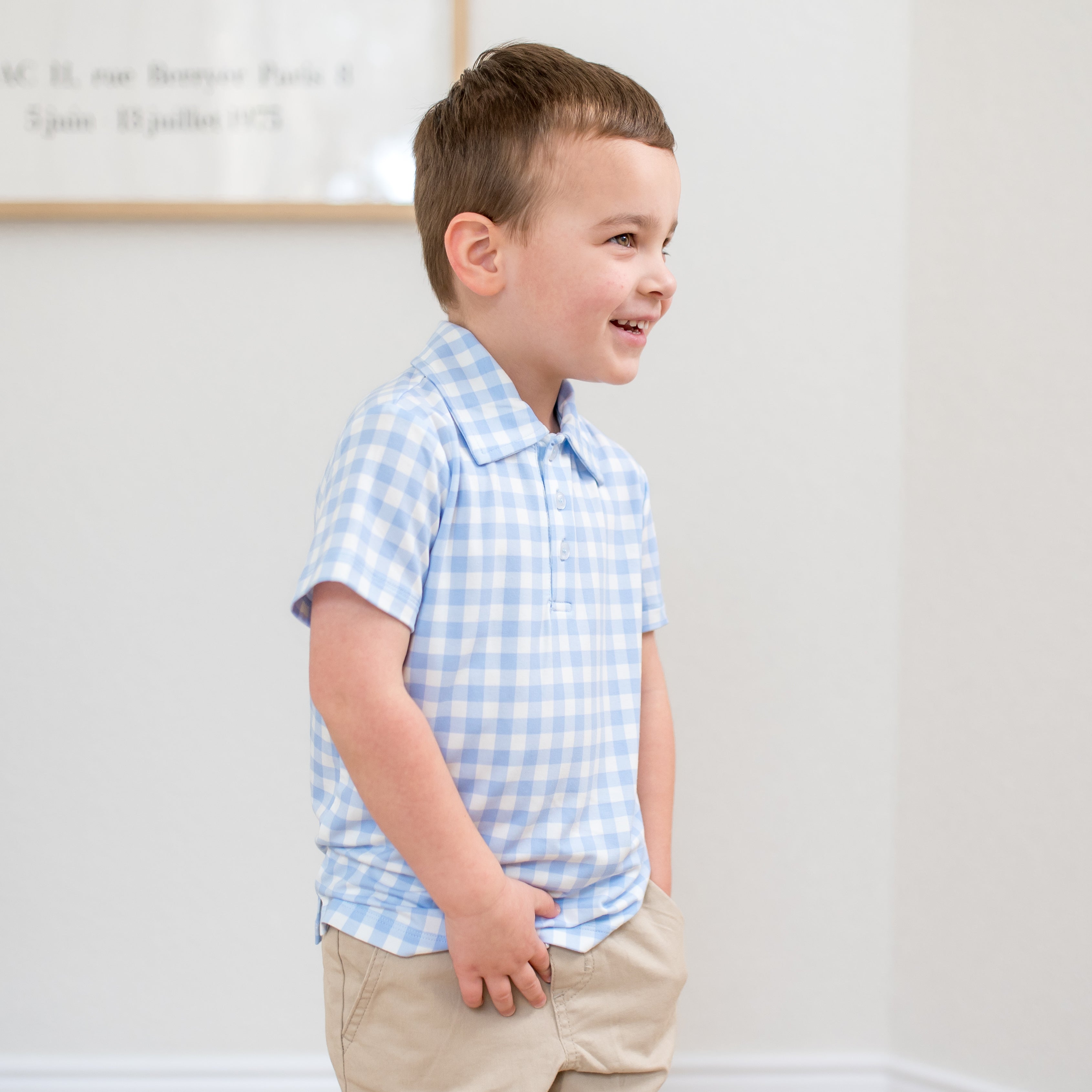 Young boy walking walking wearing the Toddler Short Sleeve Polo in Gingham Breeze with khaki colored pants