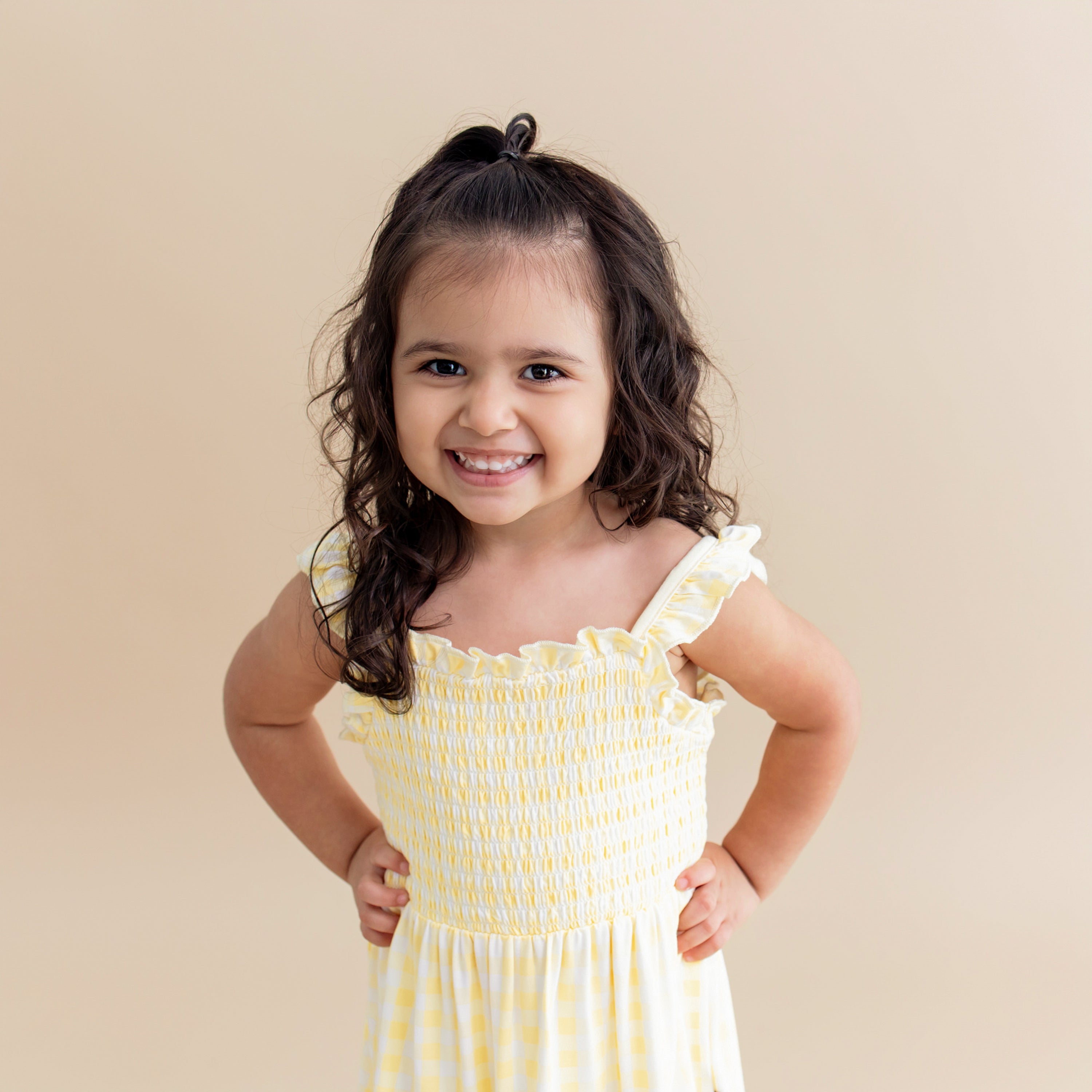 Close up of a young girl wearing the Smocked Dress in Gingham Chamomile showing the smocked bodice