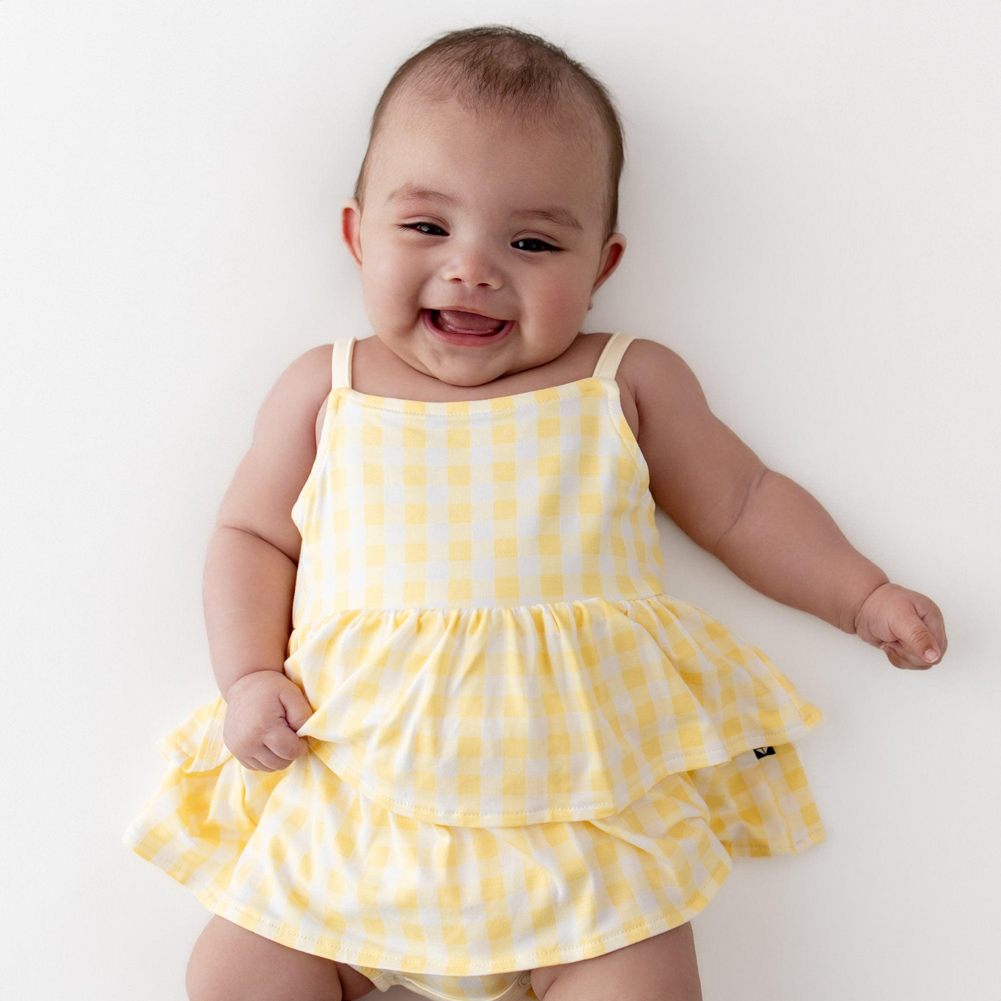 Close up of smiling infant wearing the Spaghetti Strap Ruffle Romper in Gingham Chamomile