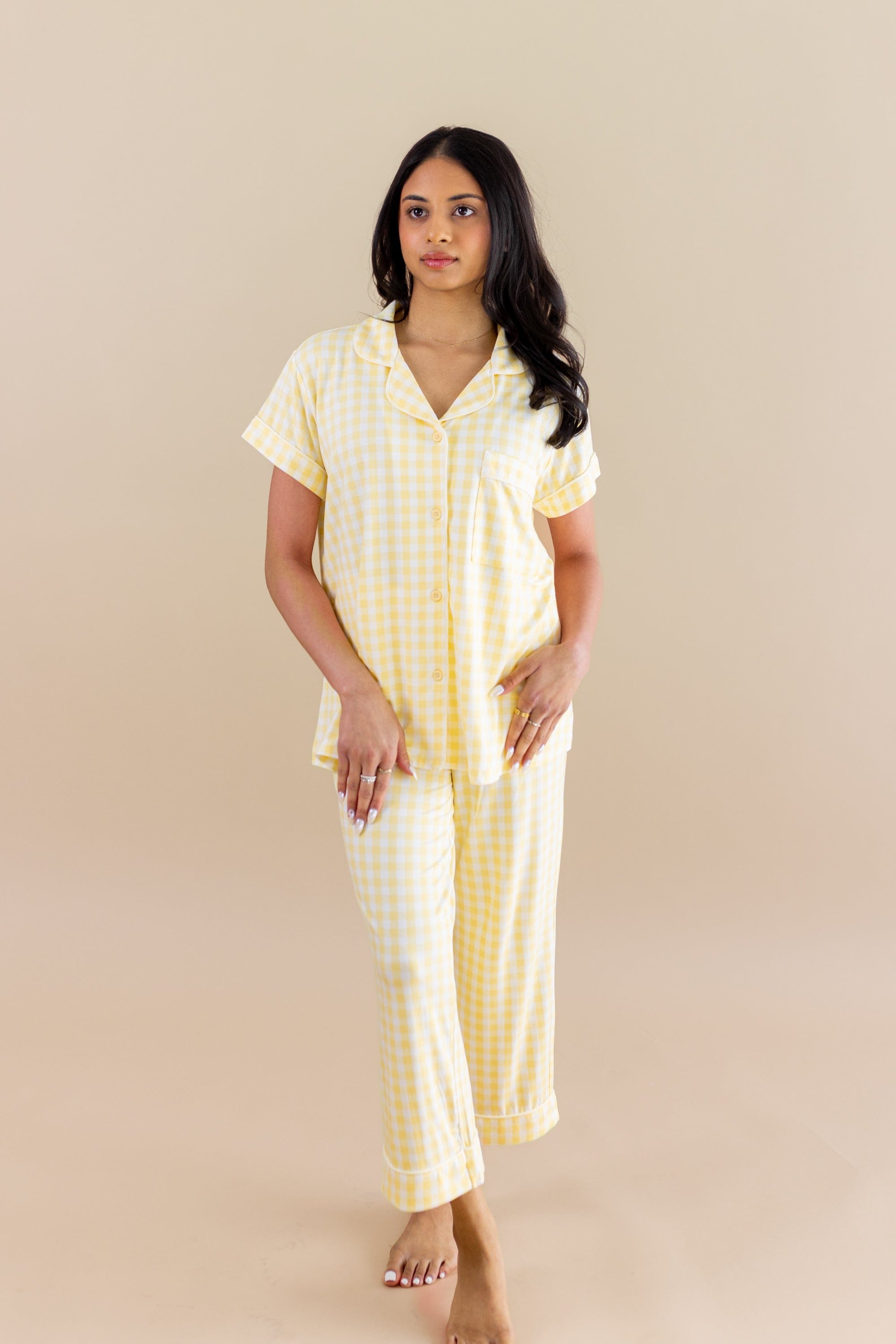 Woman wearing a yellow checkered pajama set against a beige background
