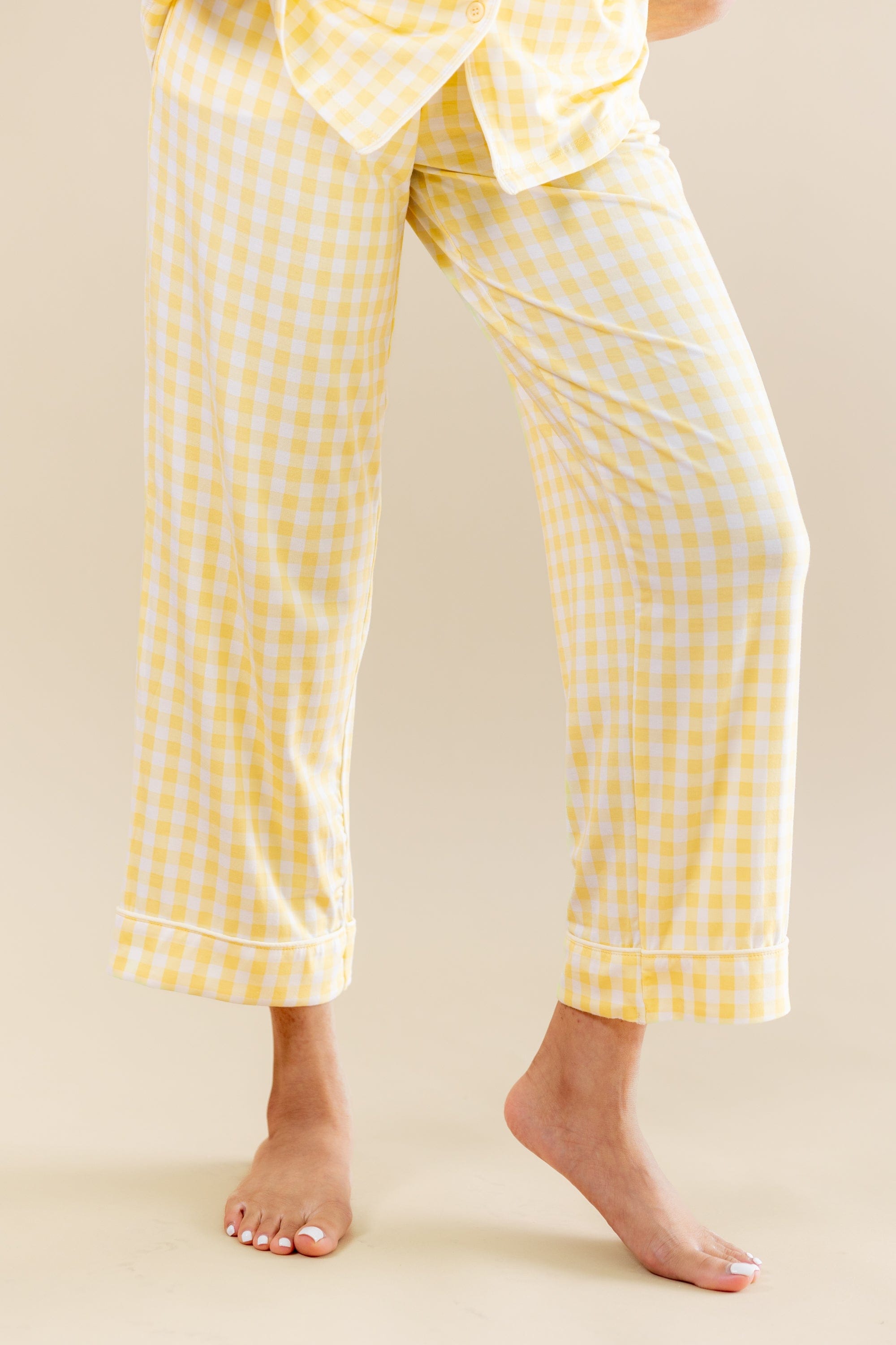 Yellow checkered cropped pajama pants worn by a person on a beige background