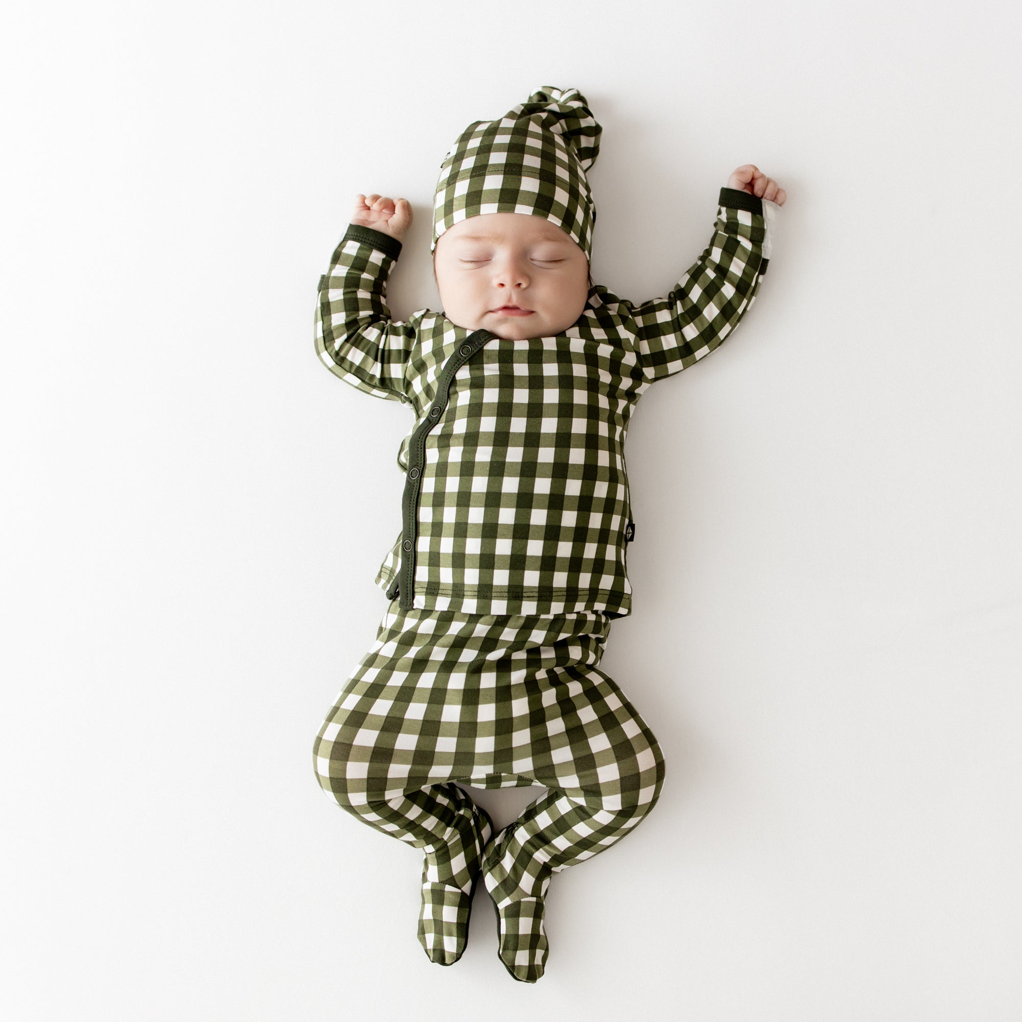 Sleeping infant laying down wearing the Take Me Home Set with Cap in Gingham Fir