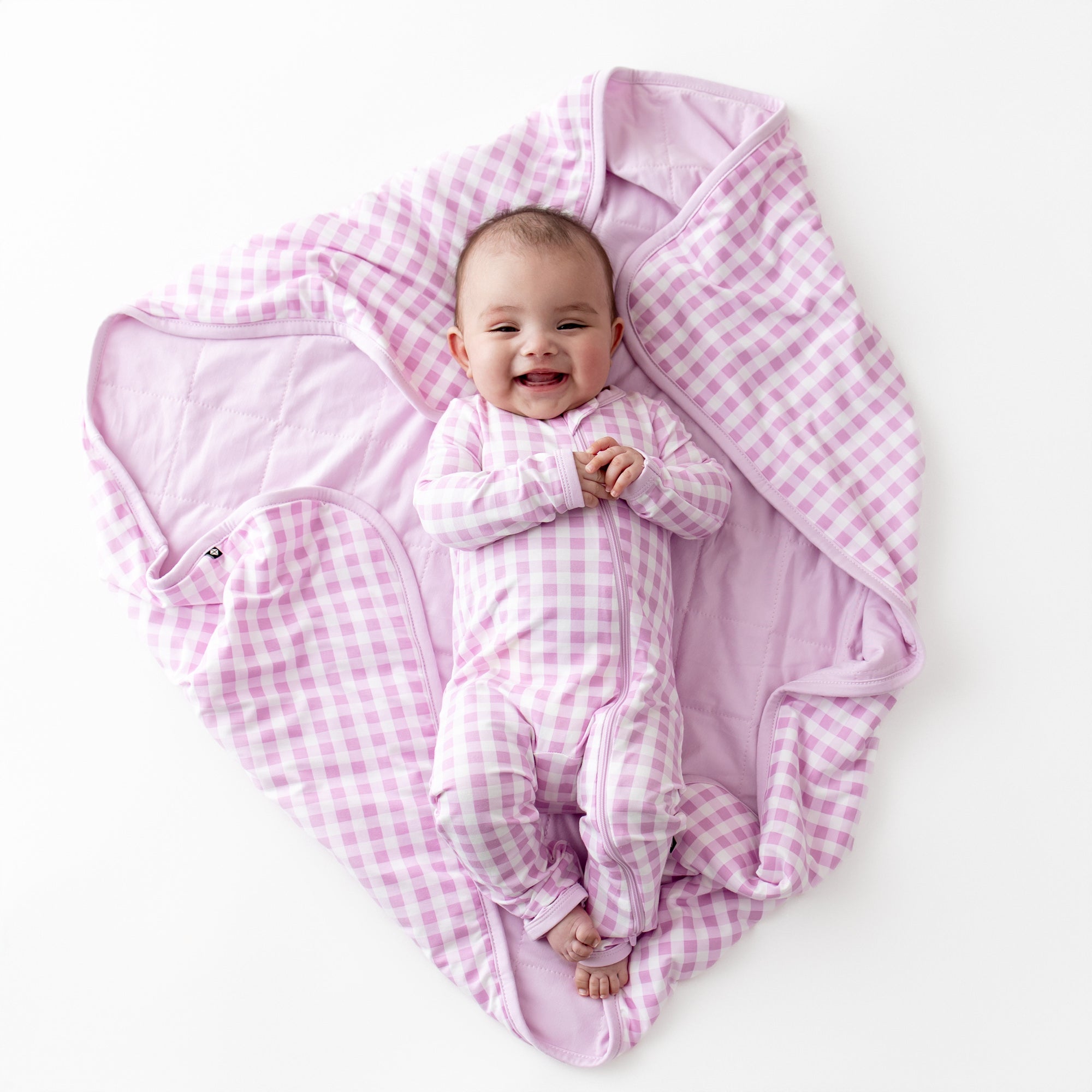 Infant laying on a Baby Blanket in Gingham Thistle wearing a matching zippered romper