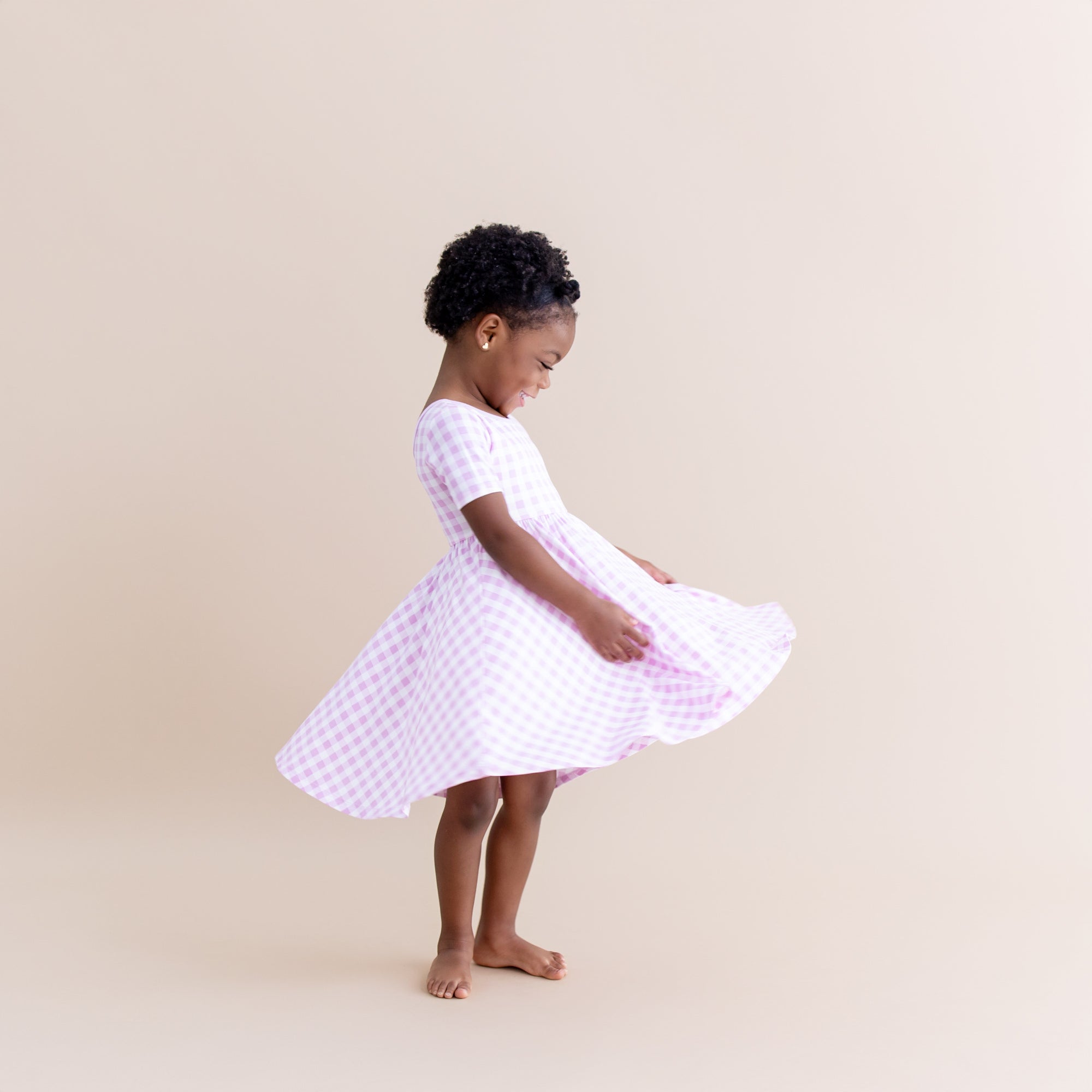 Young girl twirling wearing the Twirl Dress in Gingham Thistle