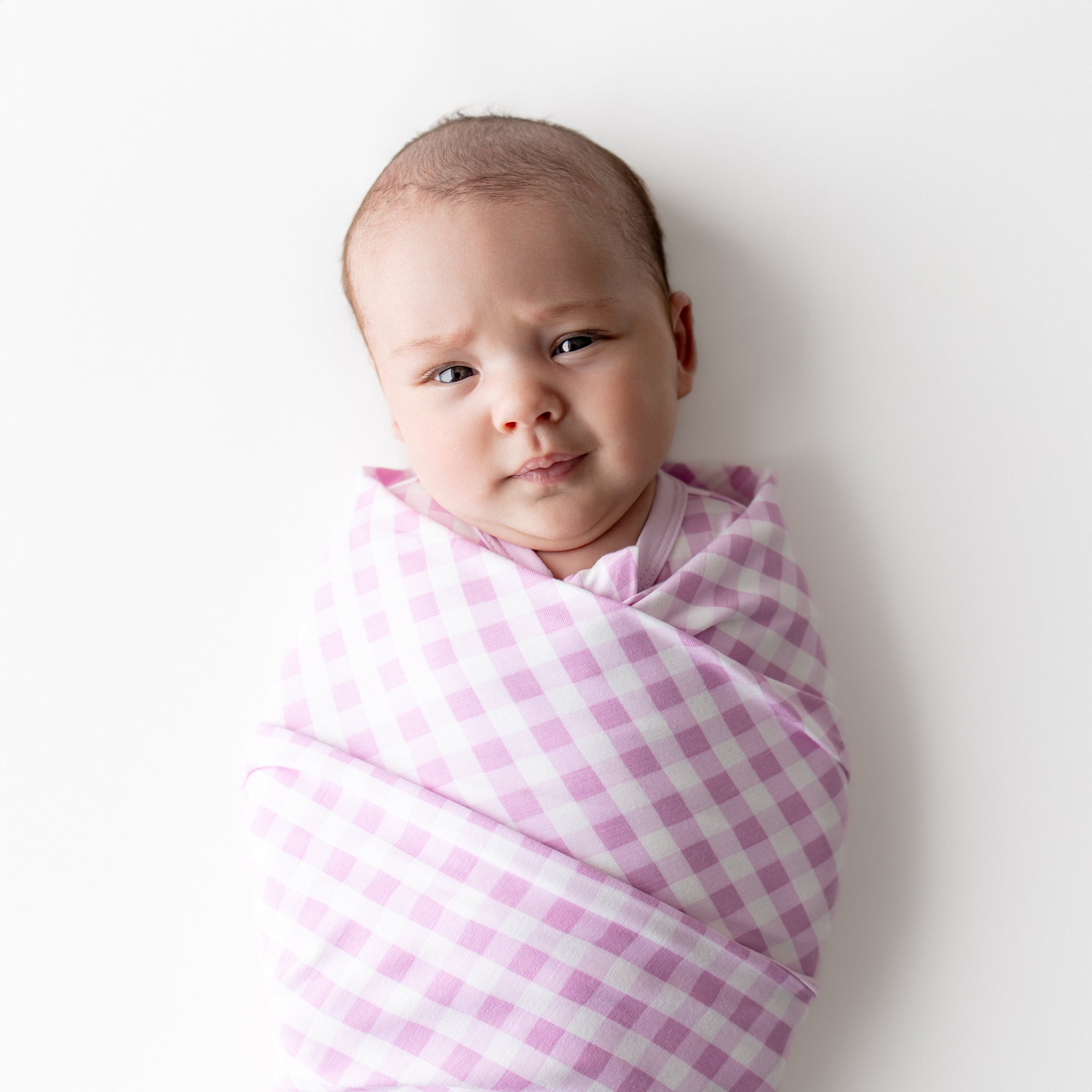 Close up of a newborn swaddled in the Swaddle Blanket in Gingham Thistle