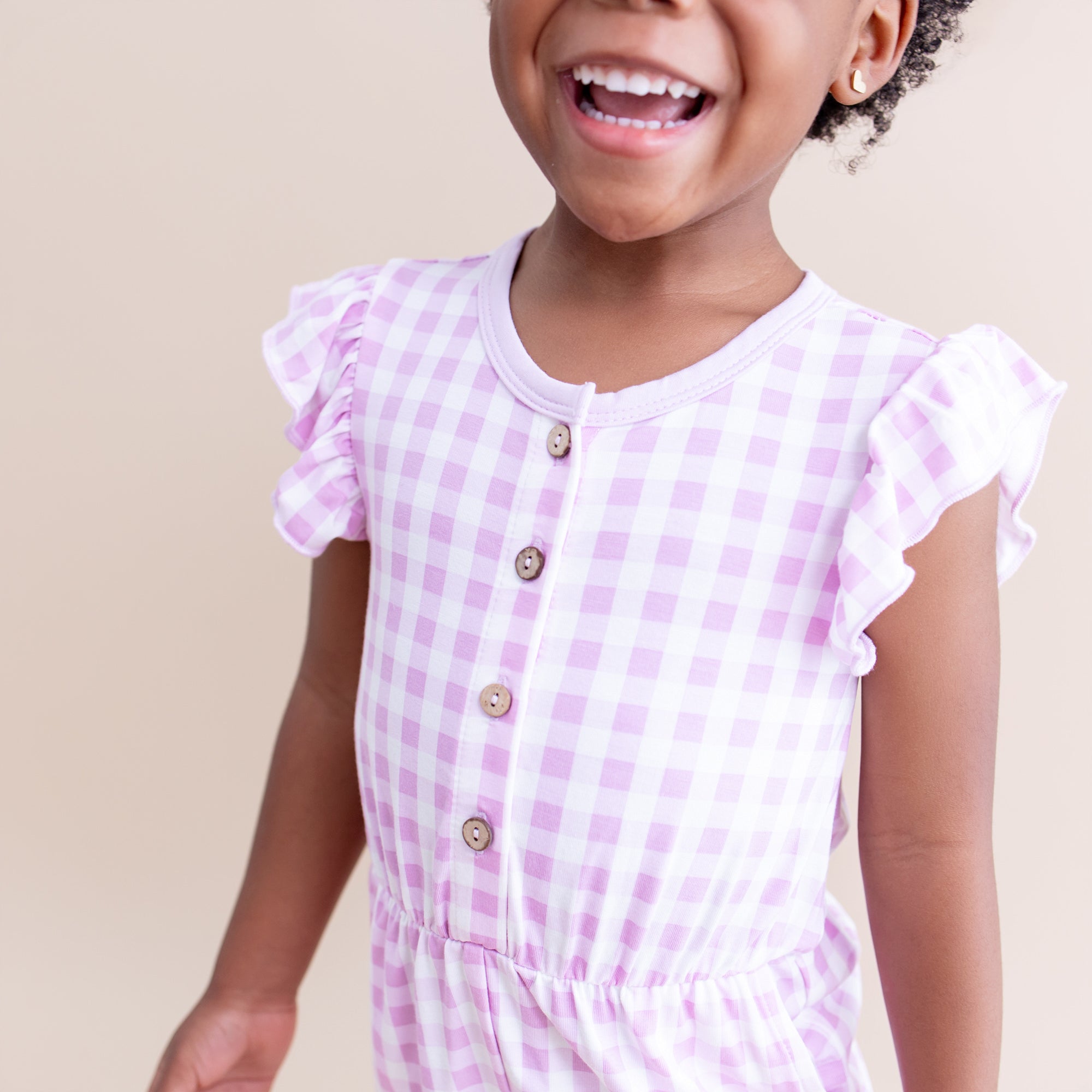 Close up of the flutter sleeves and button closures shown on the Flutter Sleeve Romper in Gingham Thistle