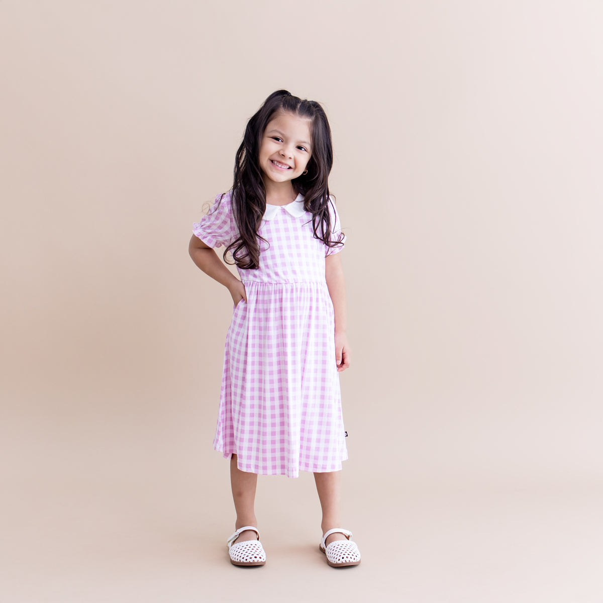 Young smiling girl posing wearing the Peter Pan Collar Dress in Gingham Thistle with white sandals