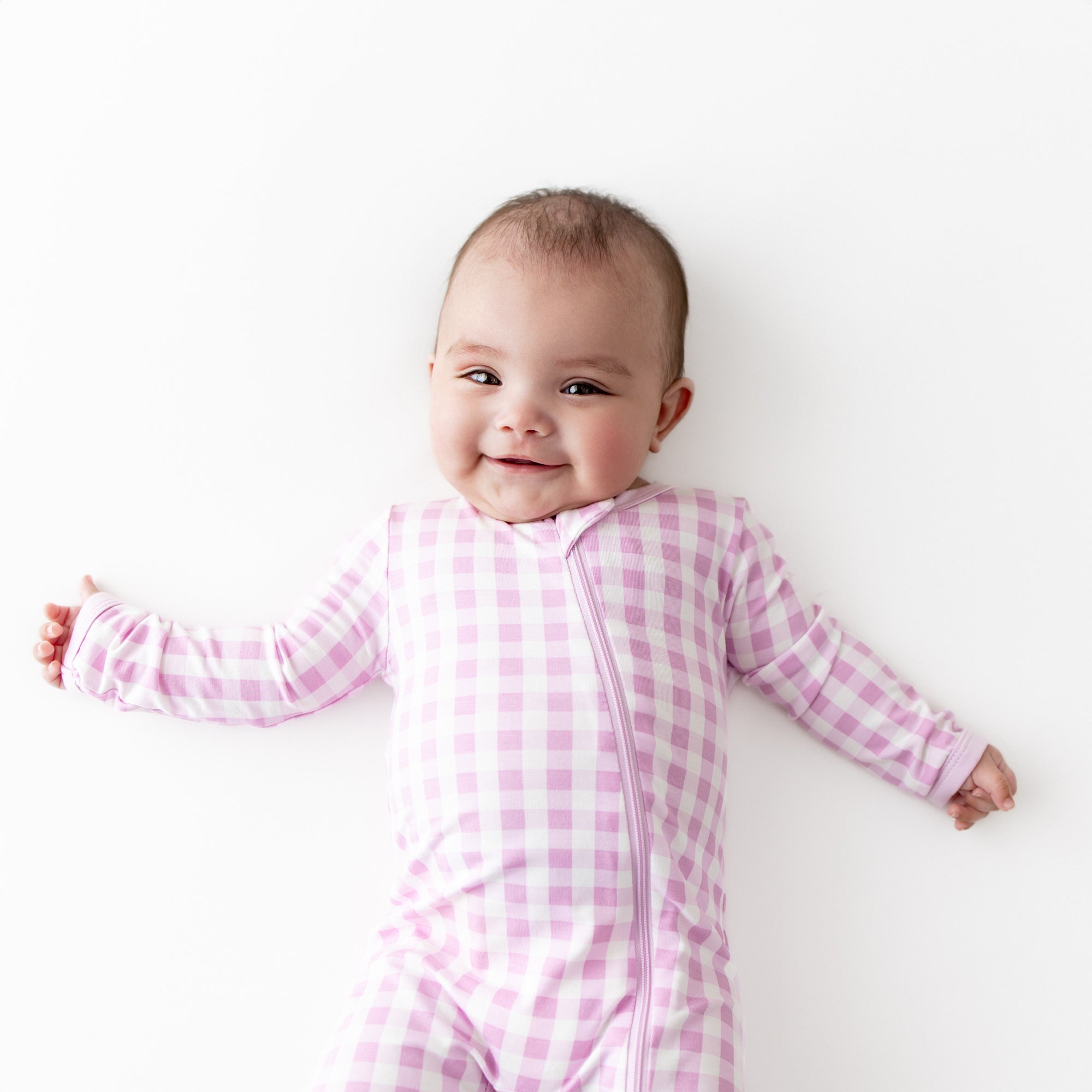 Close up of smiling infant wearing the Zippered Romper in Gingham Thistle