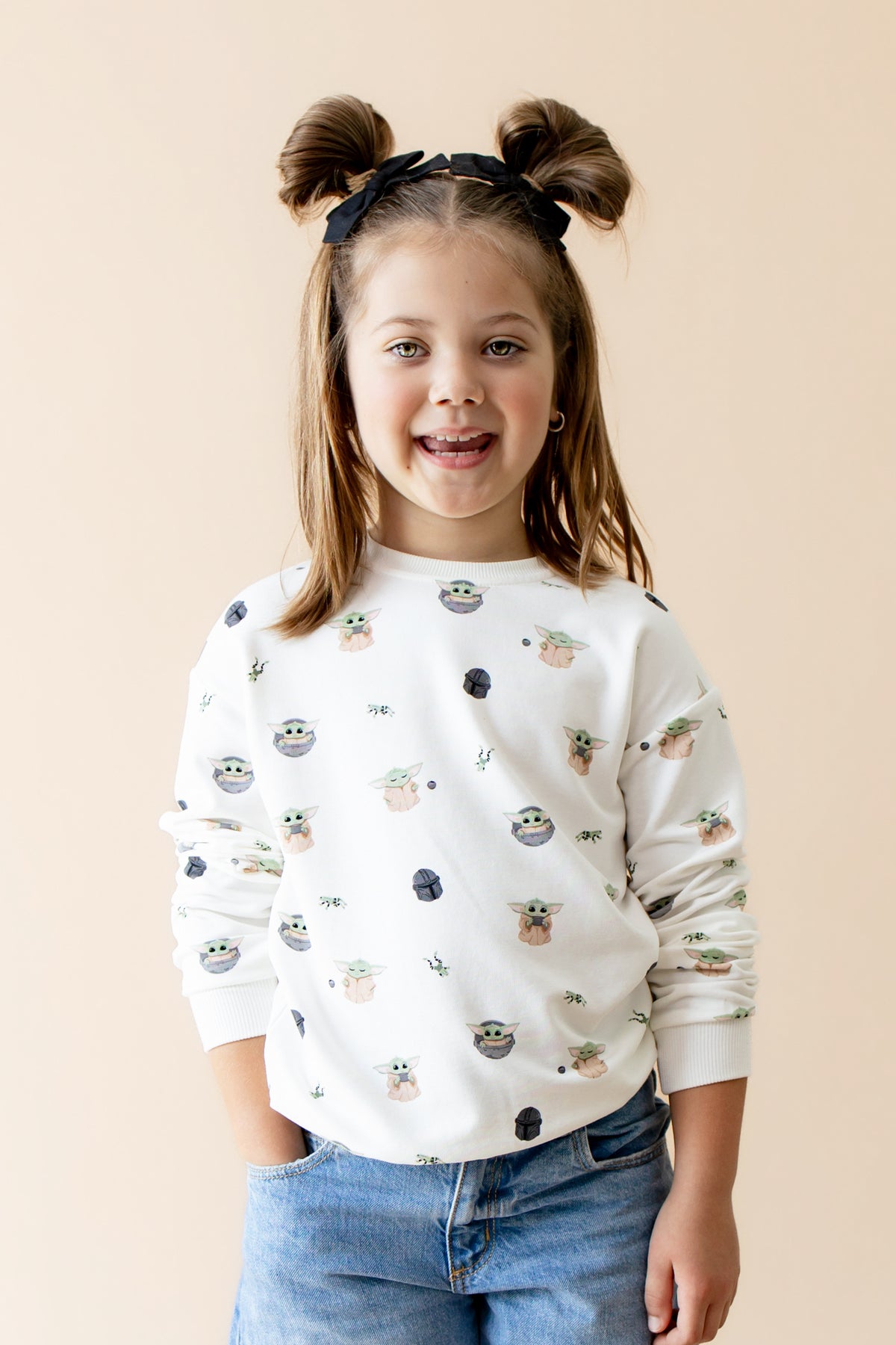 Young girl modeling the Sweatshirt in Grogu™ paired with light wash jeans