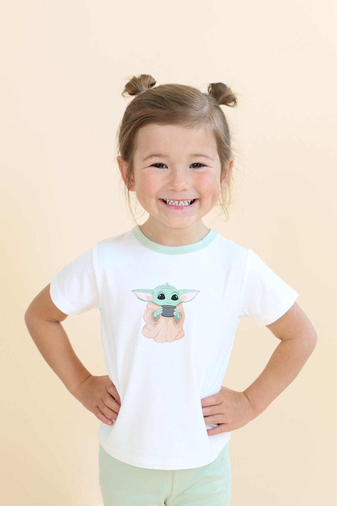 Young smiling girl wearing the Toddler Basic Tee in The Child™ with light green leggings