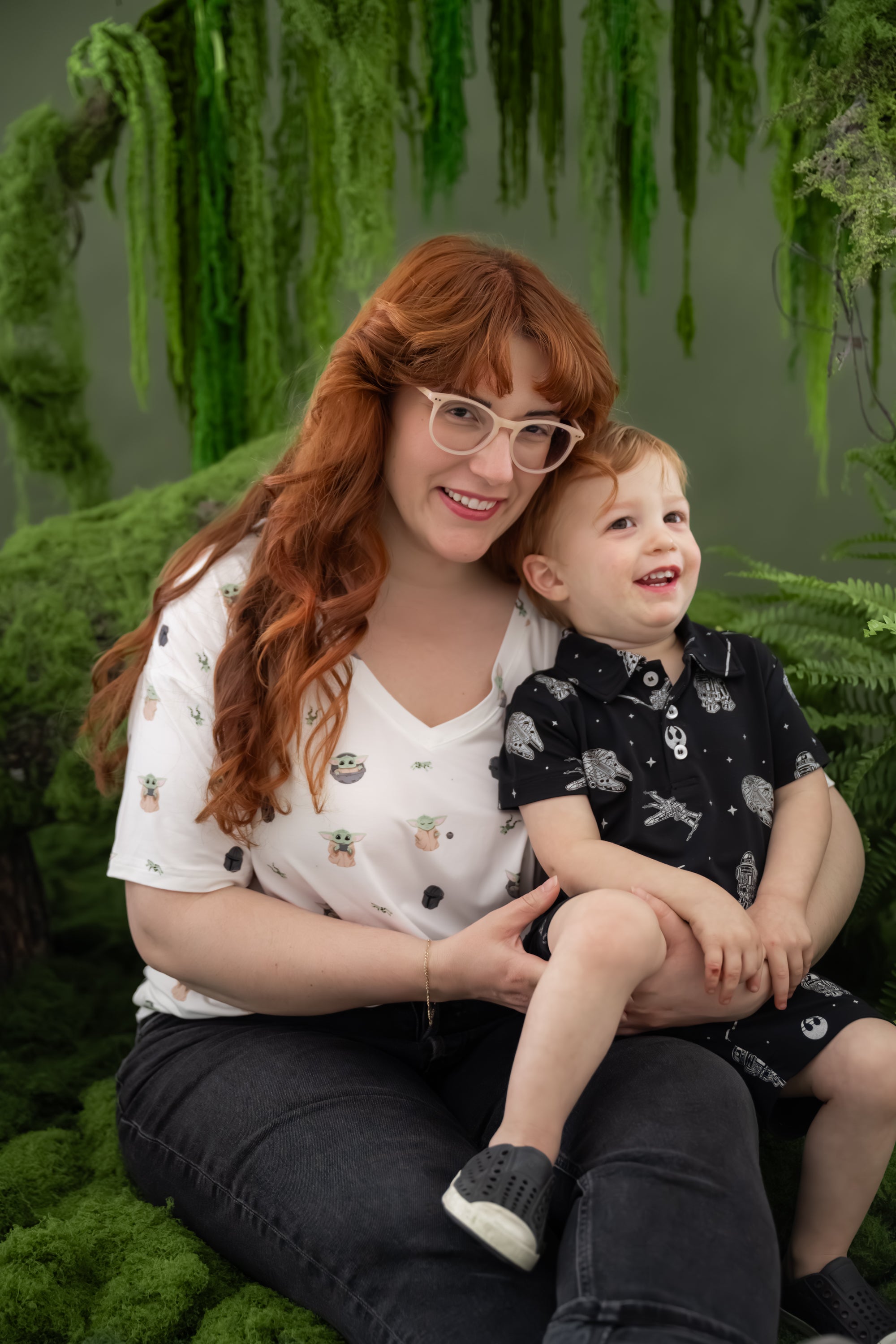 Mother wearing the Women's Relaxed Fit V-Neck in Grogu™ with her son sitting on her lap wearing STAR WARS short sleeve polo tee and matching drawstring shorts