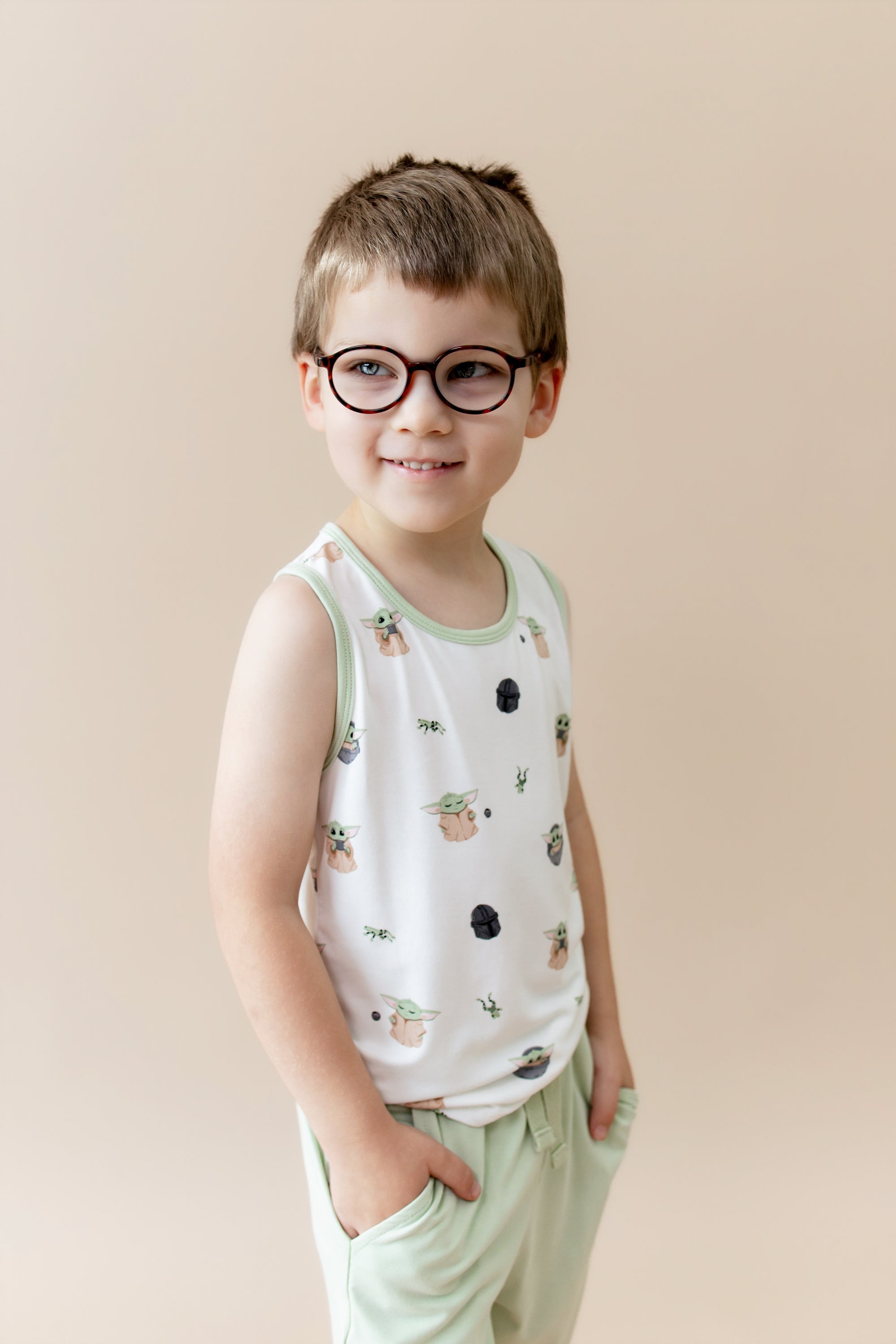Young boy modeling the Toddler Tank Top in Grogu™ paired with light green shorts