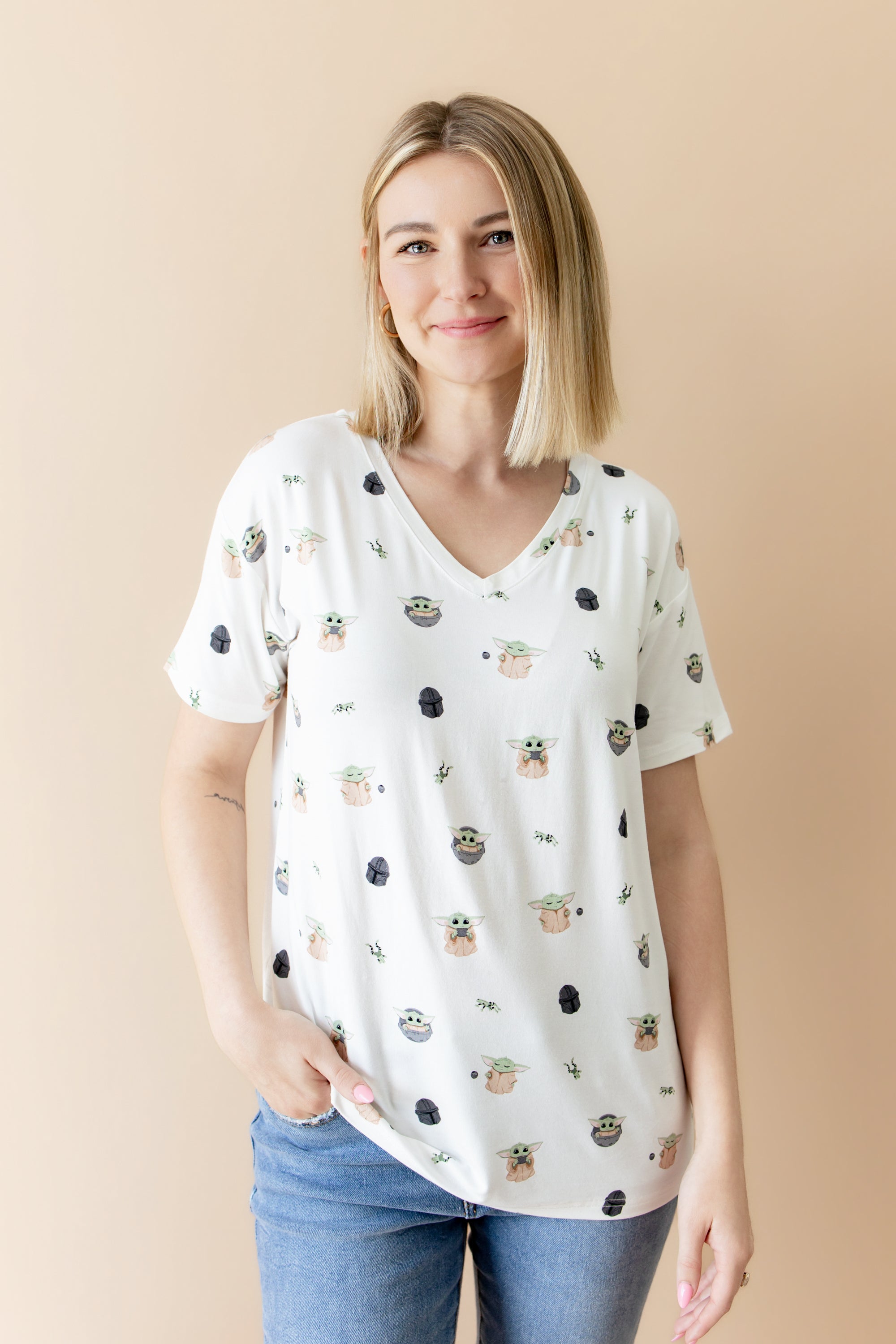 Smiling female model posing wearing the Women's Relaxed Fit V-Neck in Grogu™ with medium wash jeans