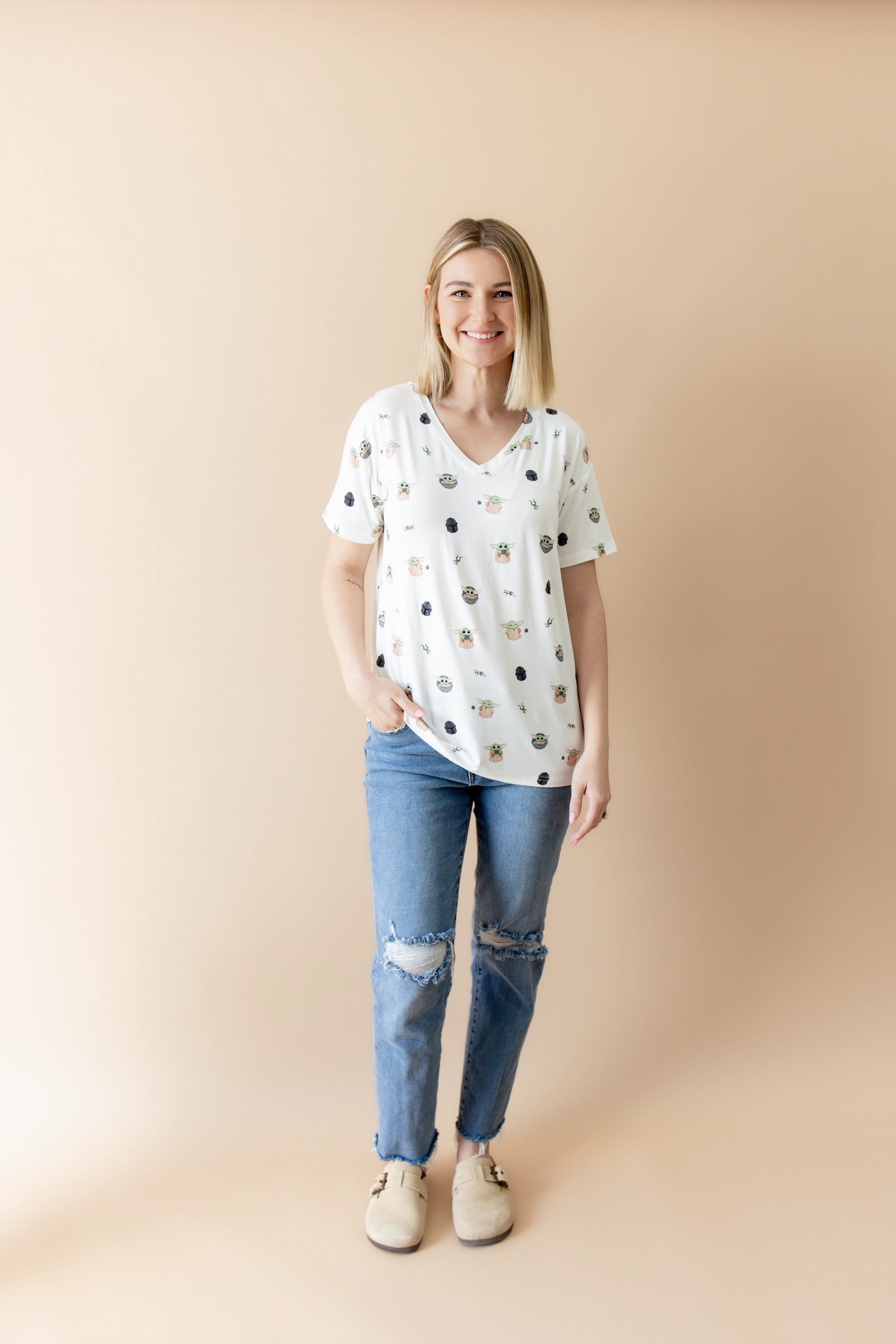 Smiling female model posing wearing the Women's Relaxed Fit V-Neck in Grogu™ with medium wash jeans