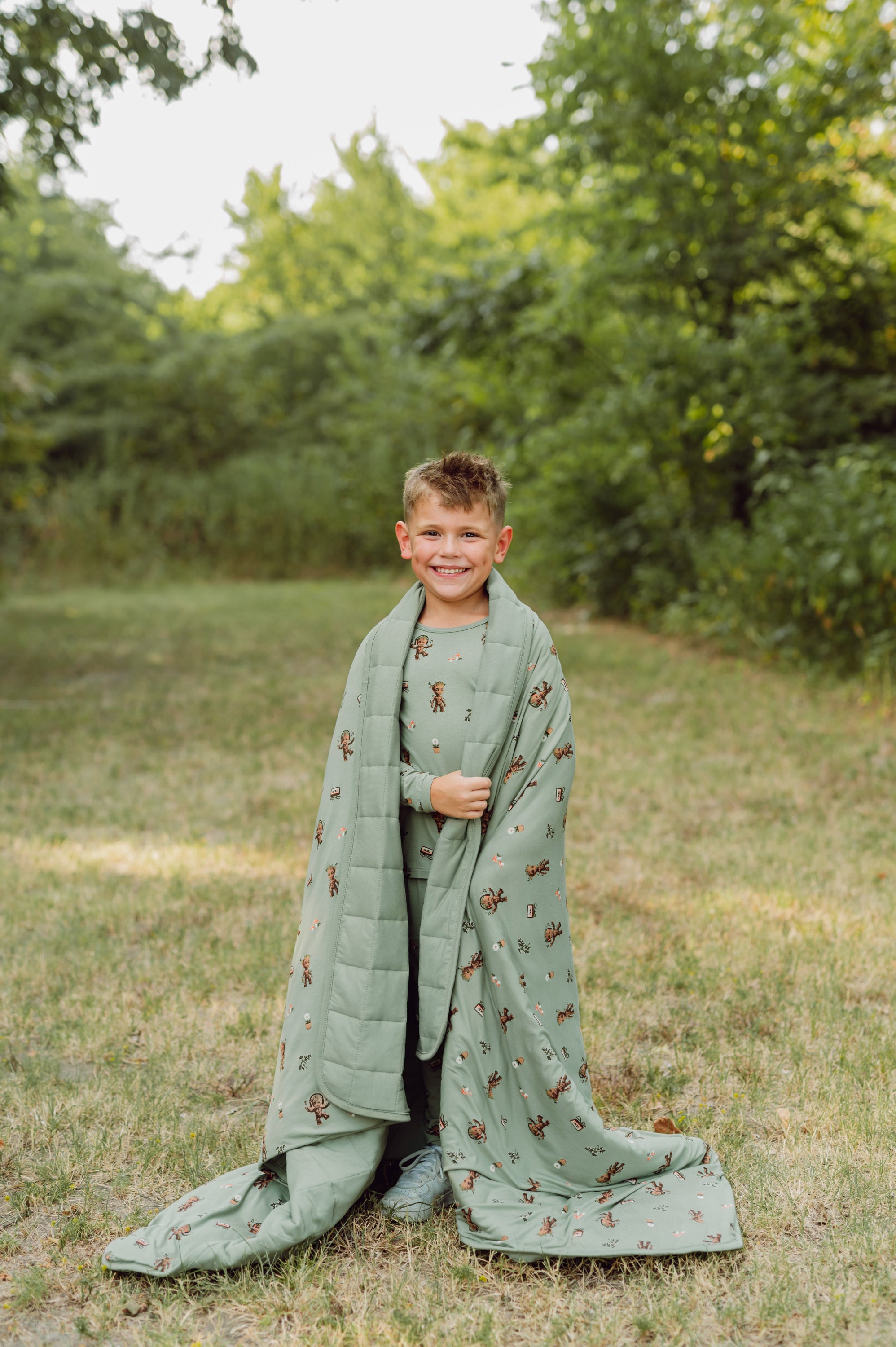 Boy outside with groot blanket over his shoulders.