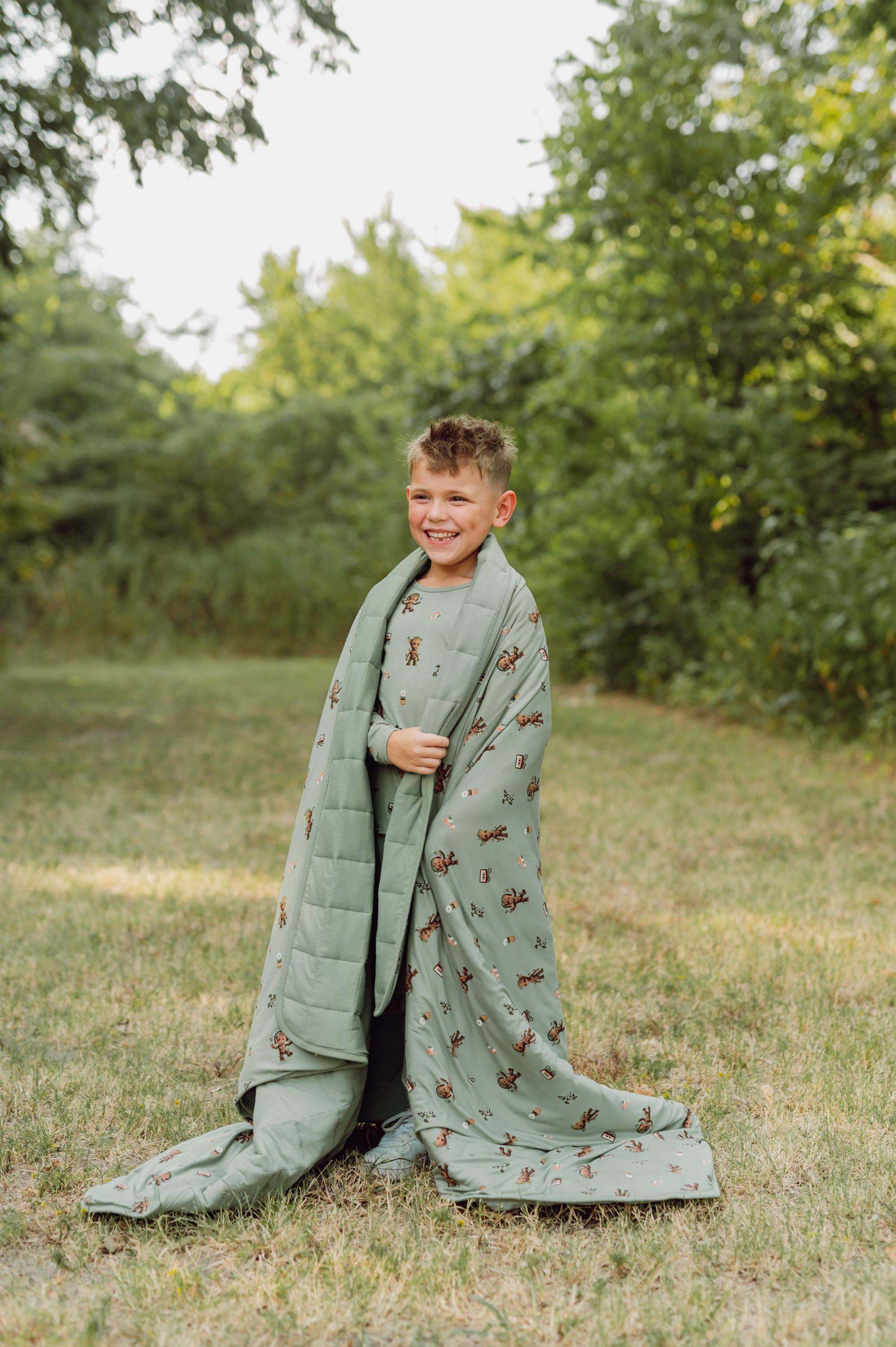 Boy outside with groot blanket over his shoulders.