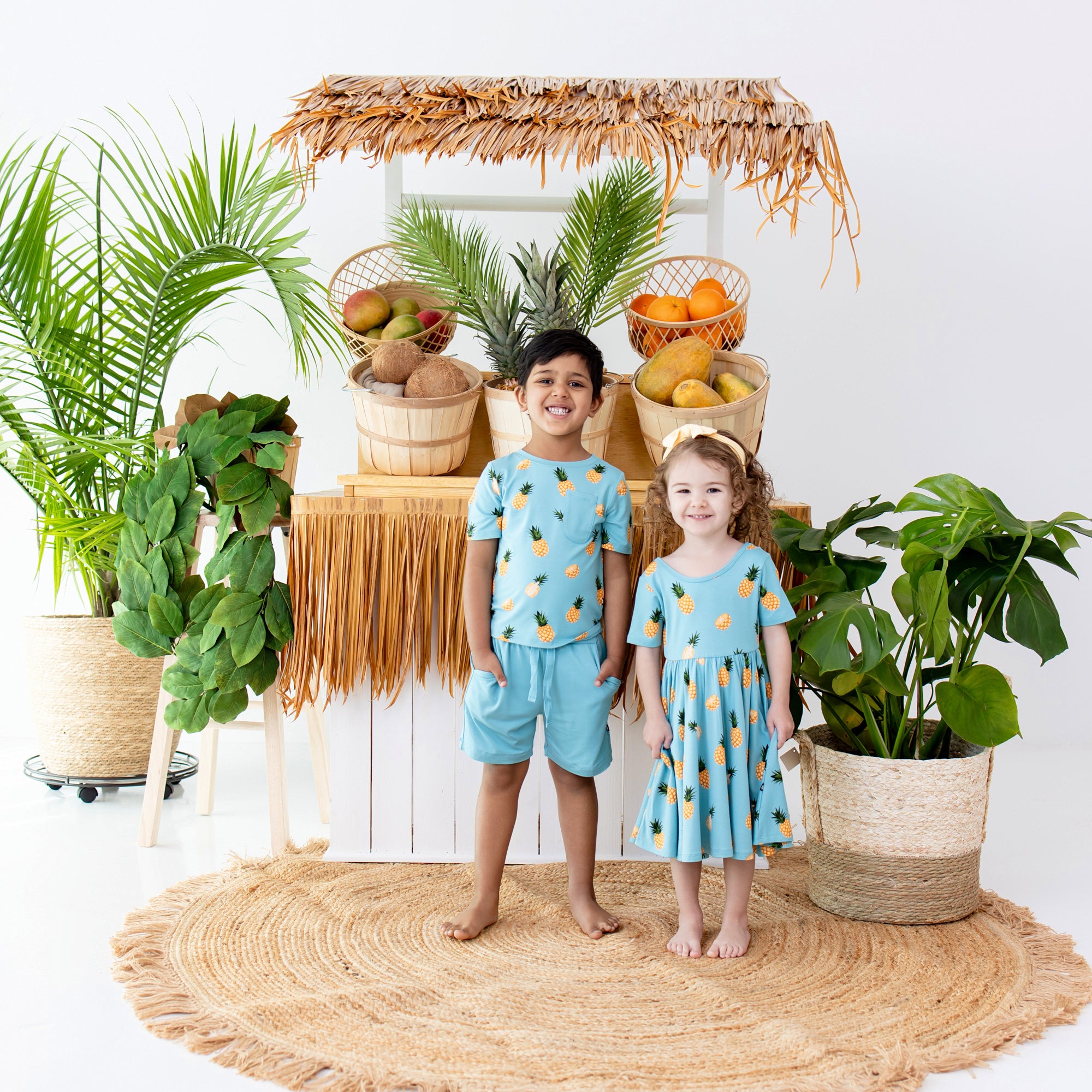 2 toddlers wearing Toddler Crew Neck Tee in Pineapple and Makai Drawstring Shorts and toddler twirl dress