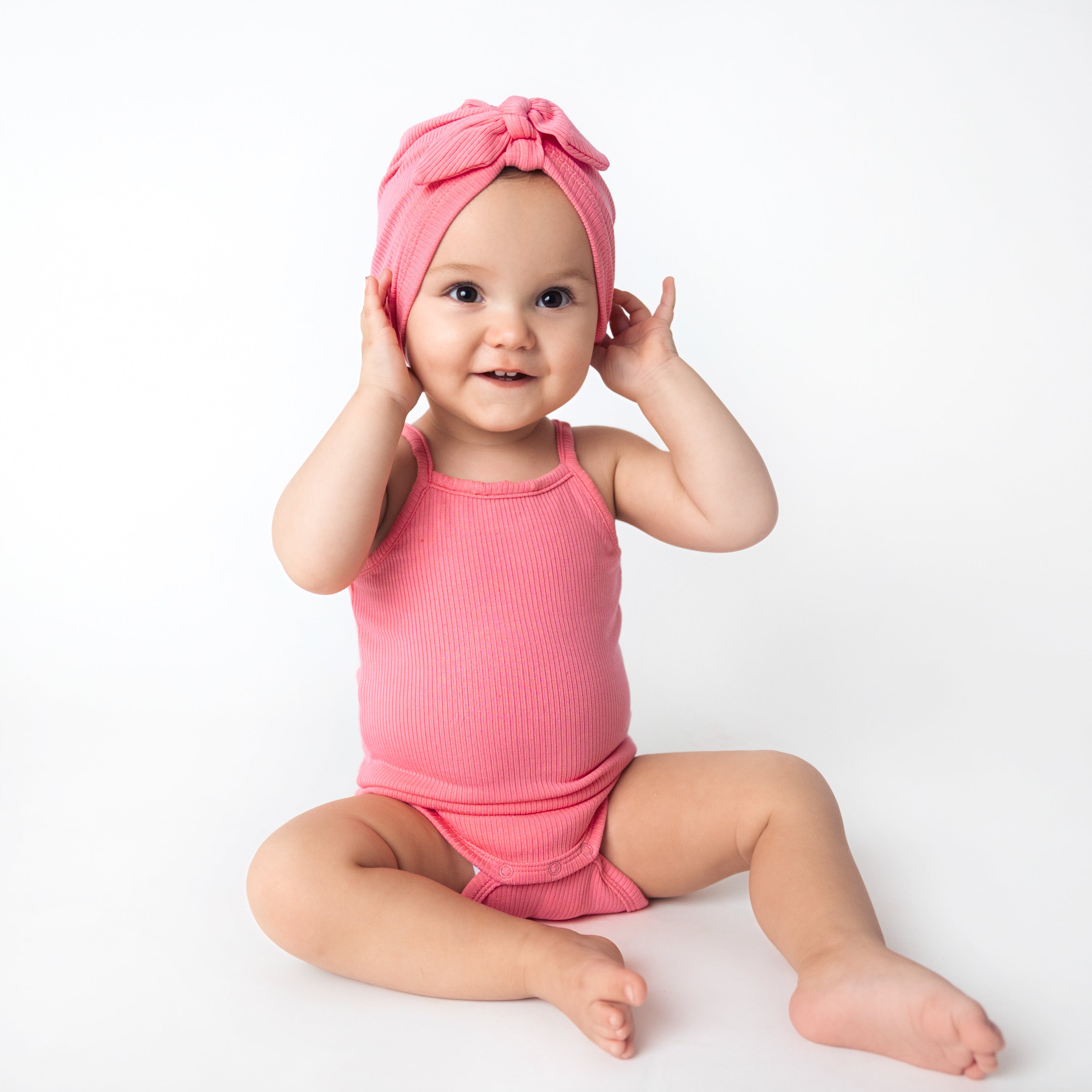 Baby wearing Ribbed Spaghetti Strap Bodysuit in Guava Pink with Bow Headwrap