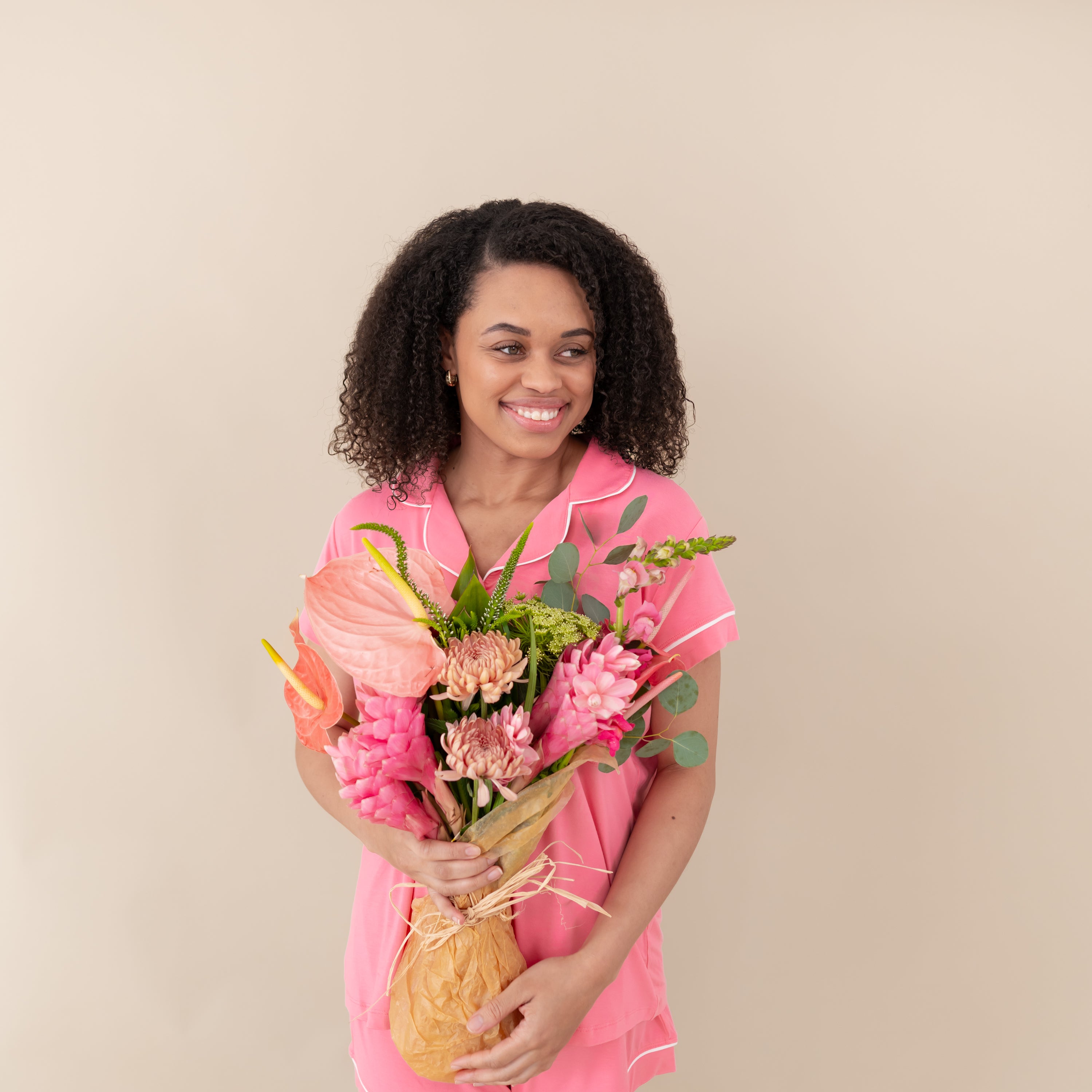 Woman modeling Women’s Short Sleeve Pajama Set in Guava with Cloud Trim holding a bouquet of flowers