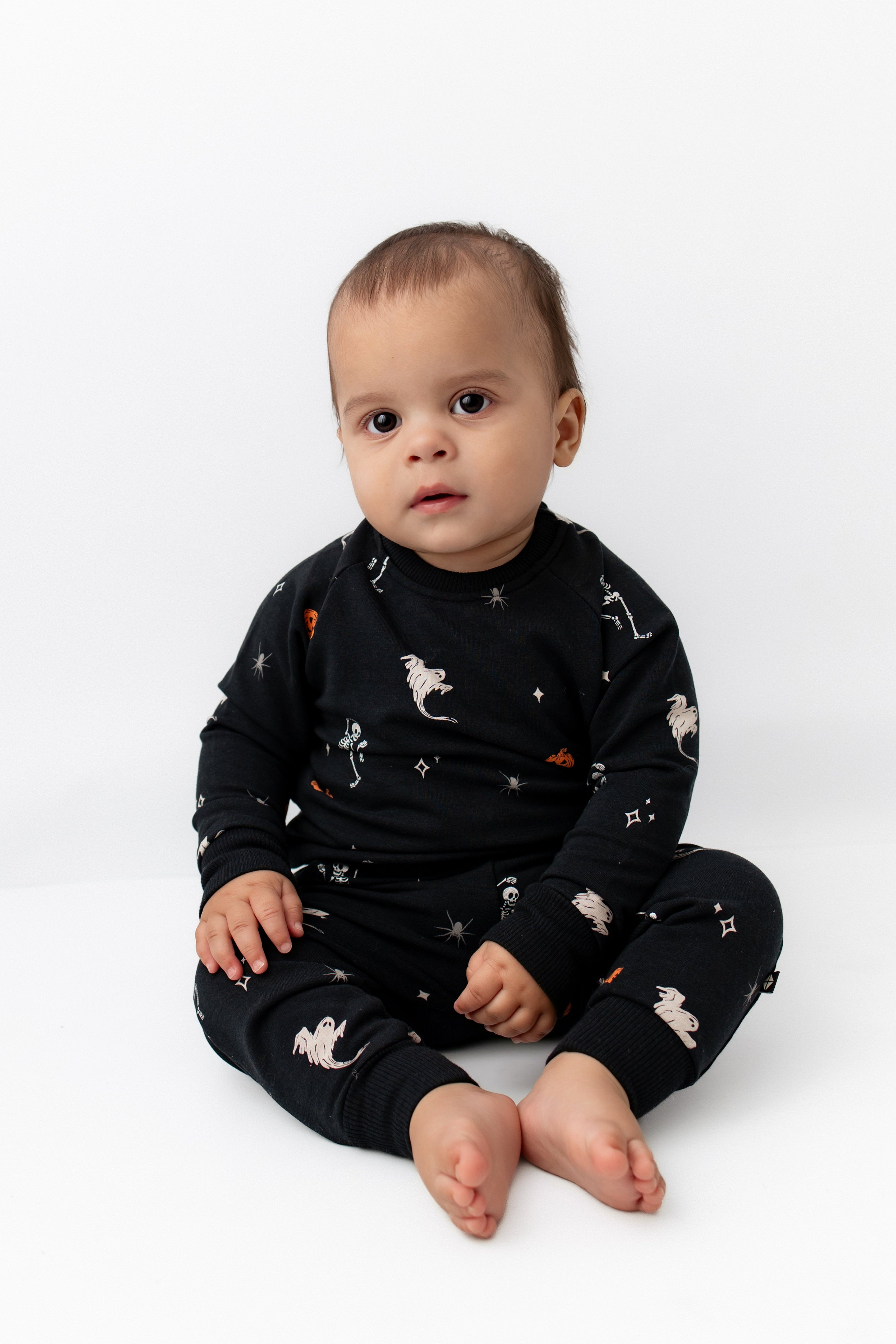 Baby wearing Long Sleeve Jogger Set in Halloween Friends print sitting on a white background