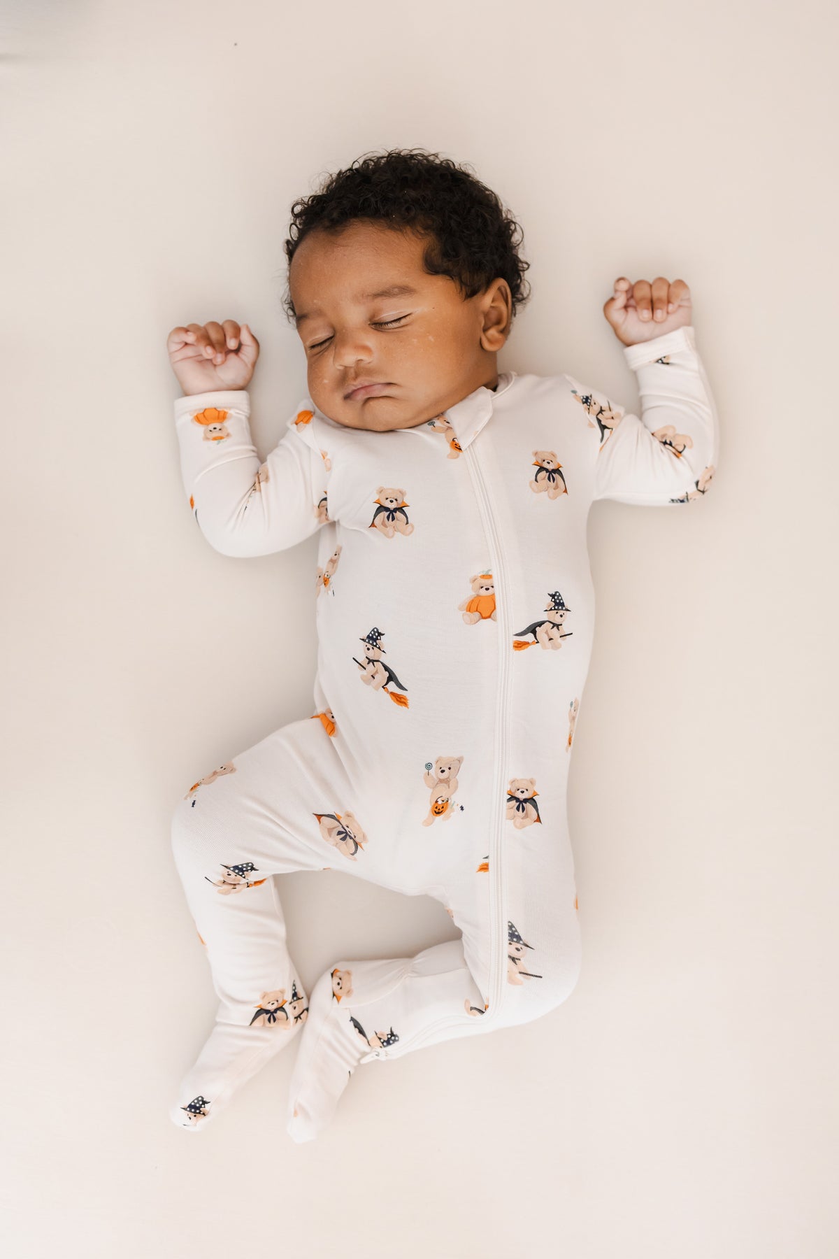 Baby sleeping in Zippered Footie in Halloween Teddy print on a beige background