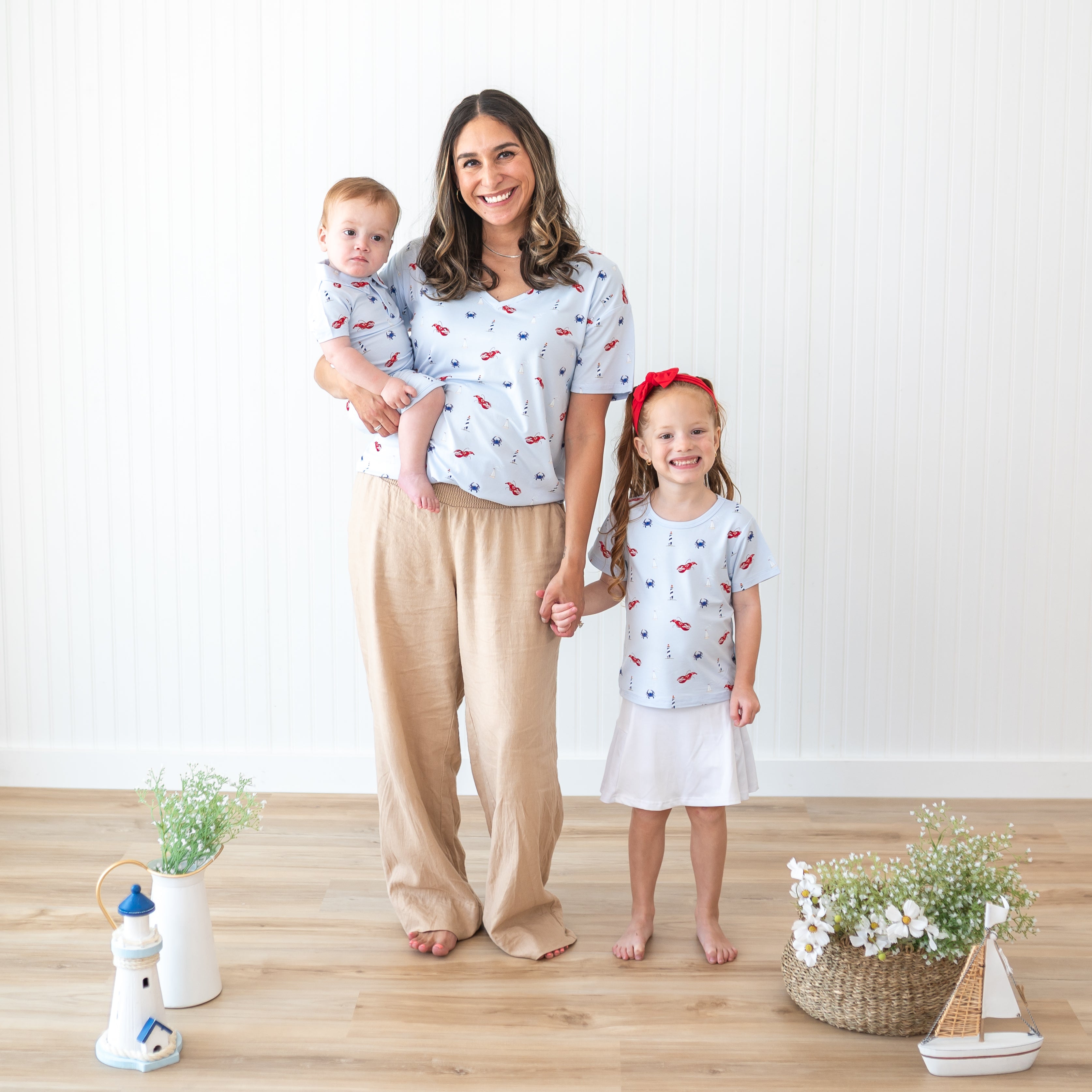 Family of three standing in front of a white paneled wall matching in items from the Harbor Collection