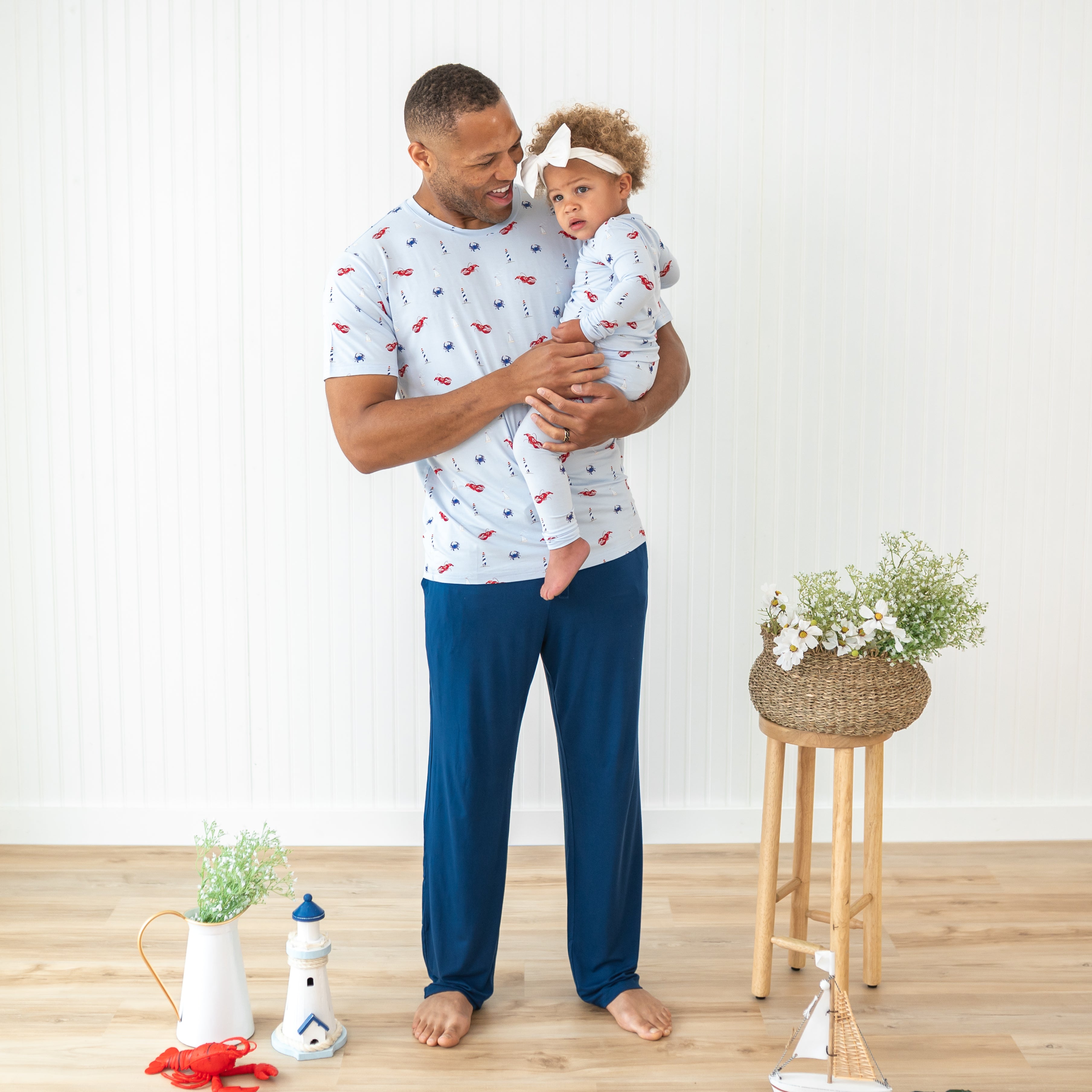 Male model wearing the Men's Crew Neck Tee in Harbor holding his daughter who is in a matching romper and Cloud Bow Headband