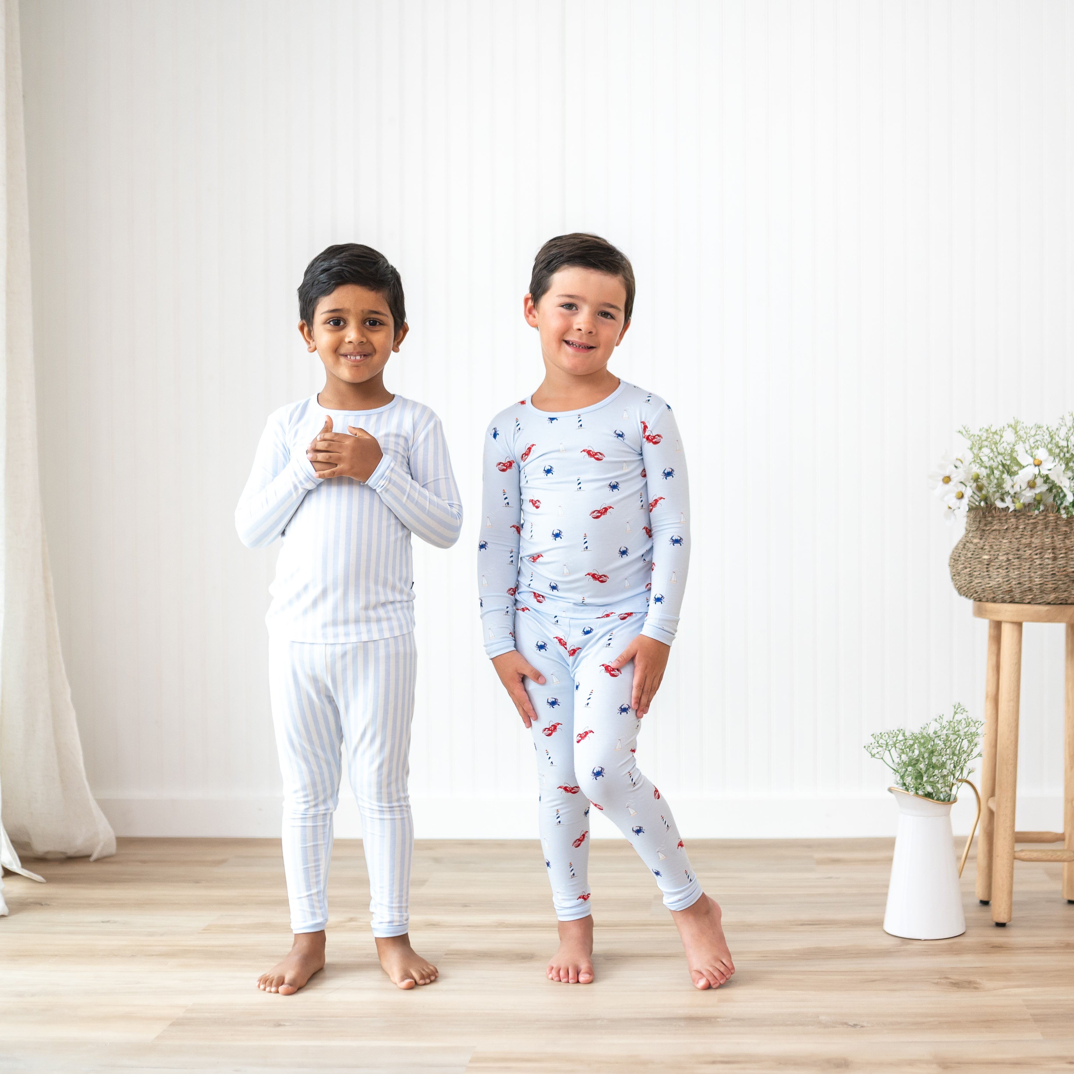 Two boy models standing side by side wearing the Long Sleeve Pajamas in Small Mist Stripe and Harbor