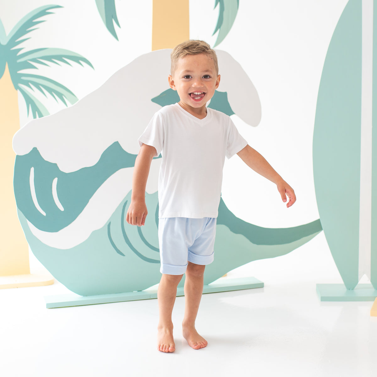 Young boy wearing the Harem Shorts in Mist paired with a Toddler V-Neck in Snow