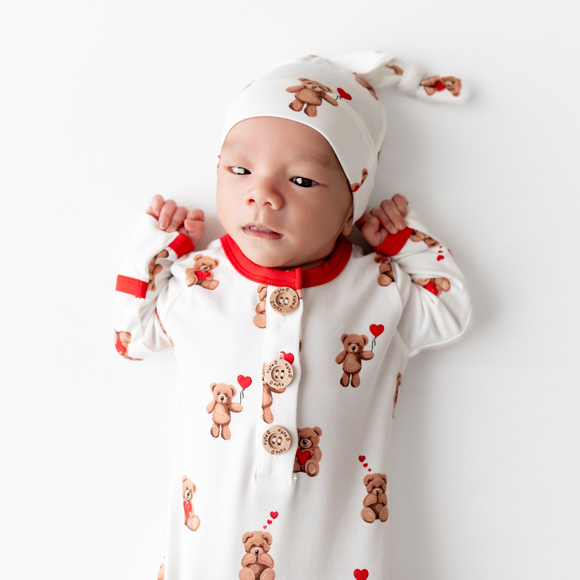 Close up of newborn laying down wearing the Knotted Gown with Hat Set in Bear Hearts