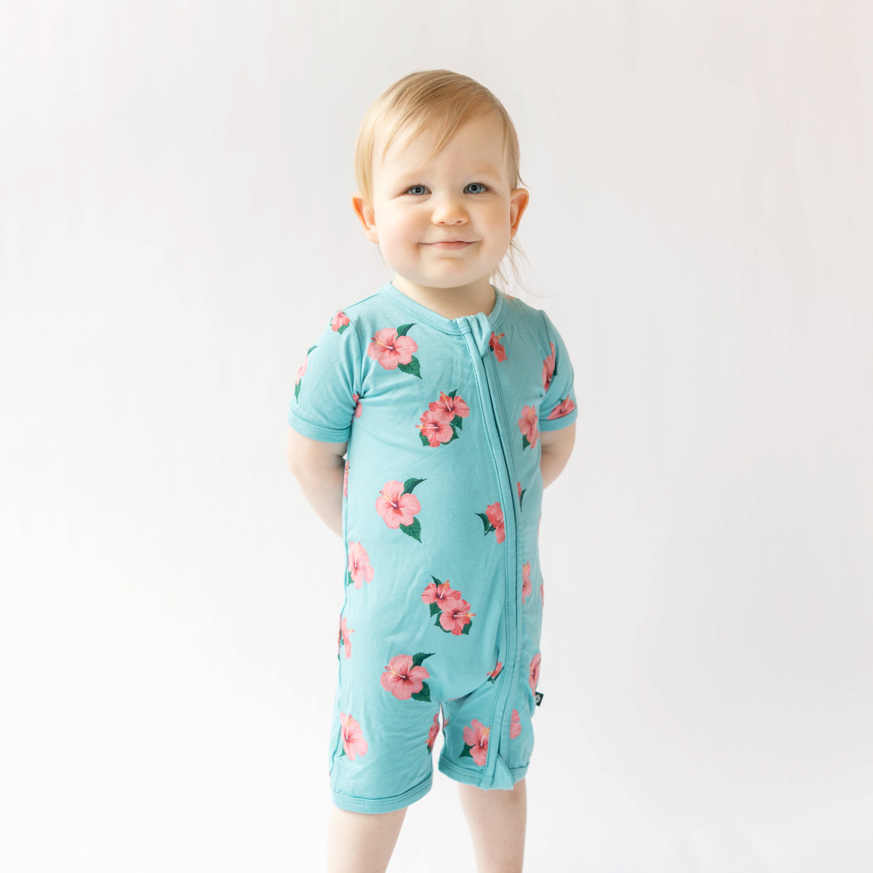 Toddler wearing Kyte Baby Zippered Shortall Romper in hibiscus