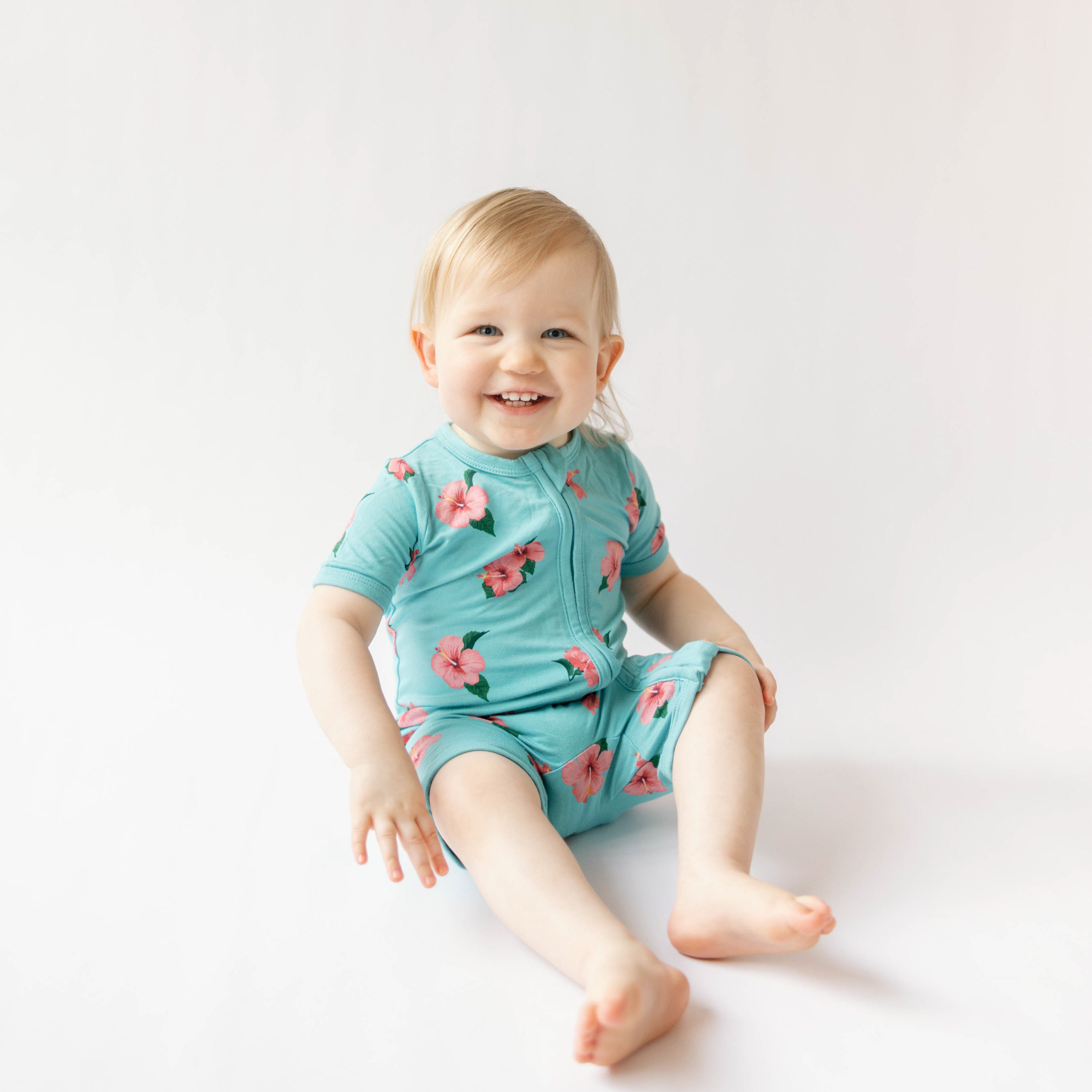 Toddler wearing bamboo Kyte Baby Zippered Shortall Romper with double zipper in hibiscus
