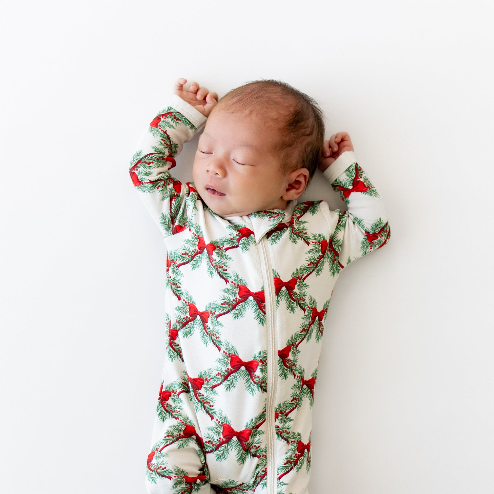 Close up of sleeping newborn wearing the Zippered Romper in Holiday Bow