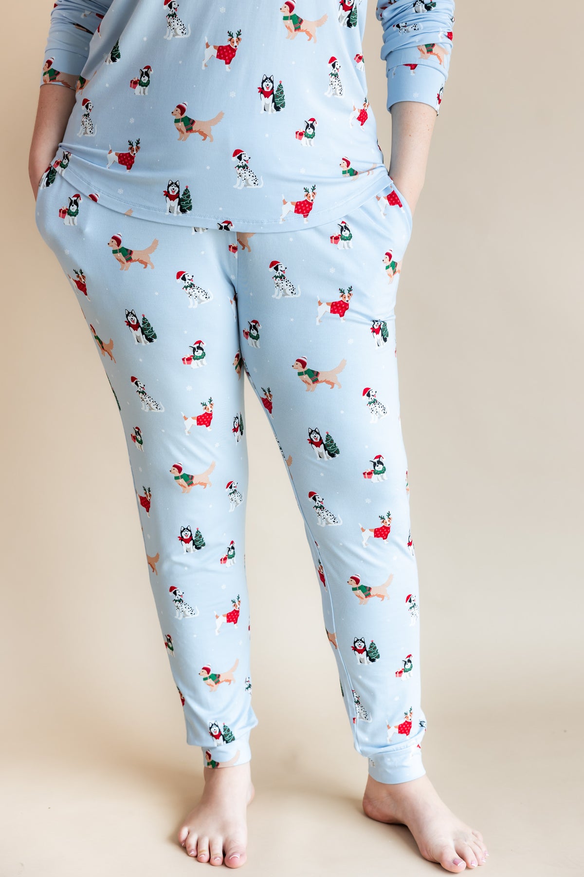 Woman showcasing the pockets on Women's Jogger Pajama Set in Holiday Pups print on a beige background