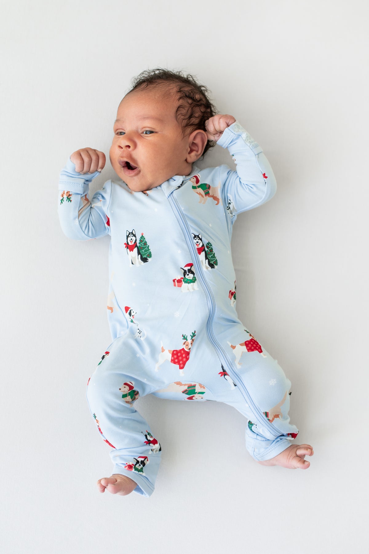 Baby wearing Zippered Romper in Holiday Pups print on a white background