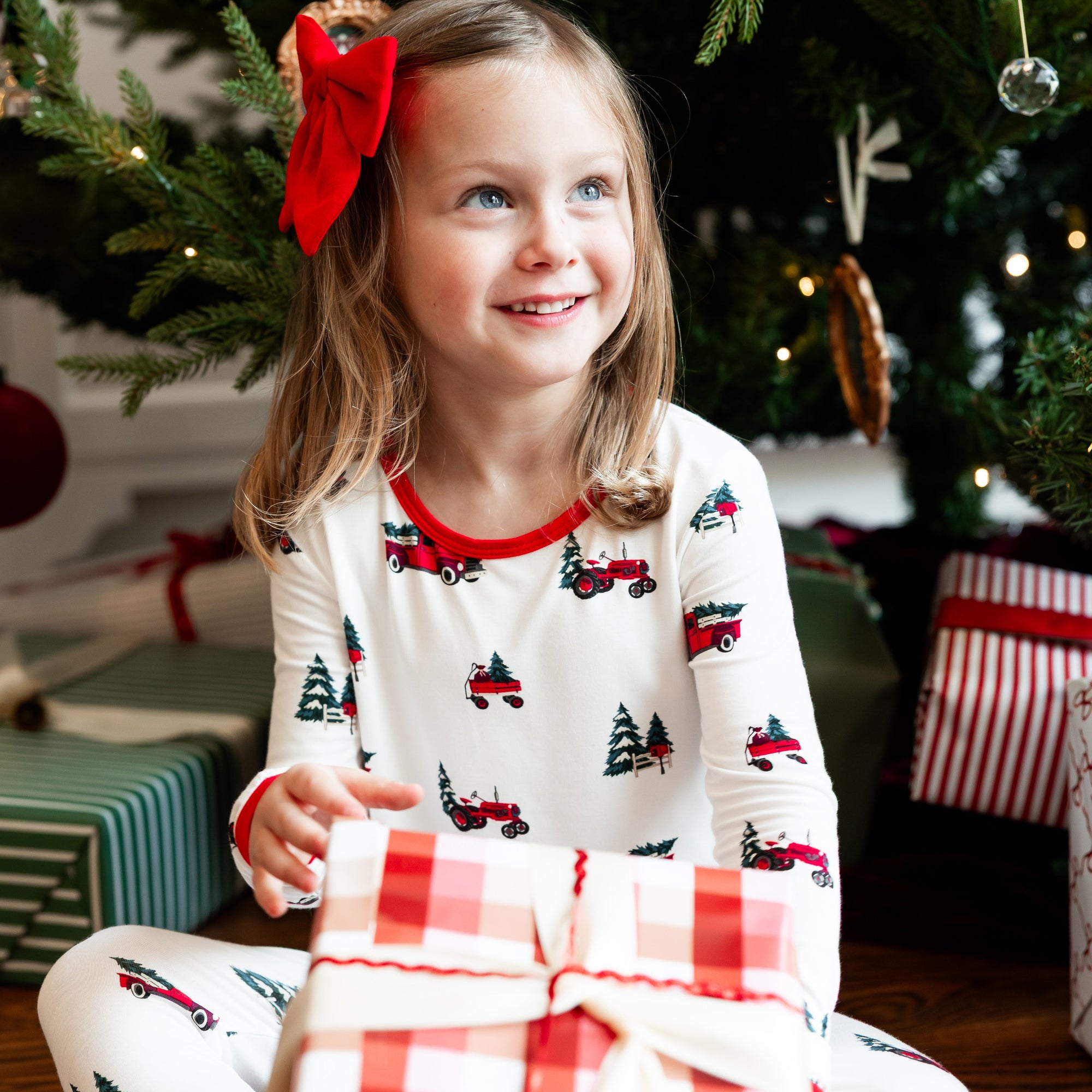 young girl in christmas pajamas holding a wrapped gift