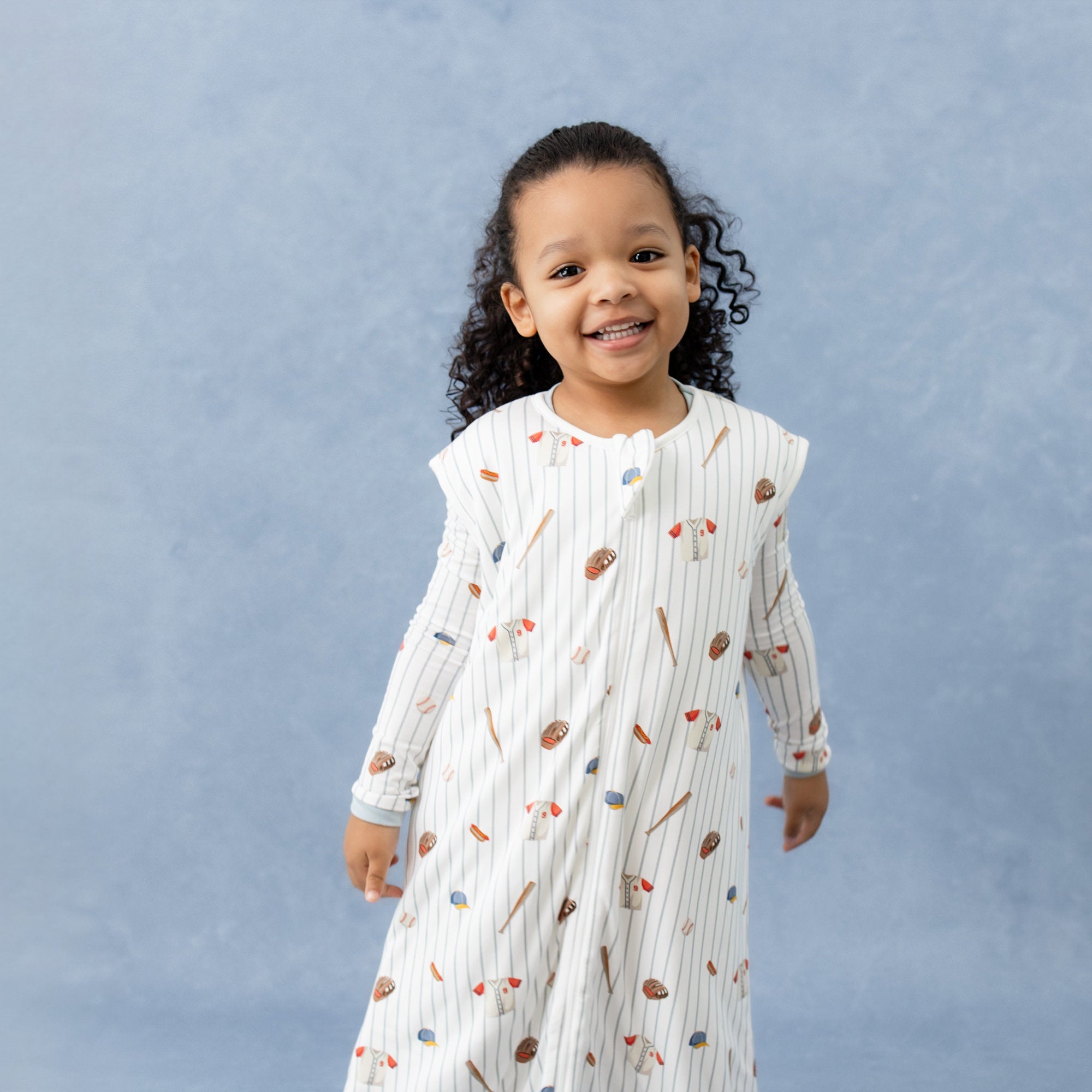 Young girl wearing the Sleep Bag Walker in Home Run 1.0 with matching long sleeve pajamas on underneath