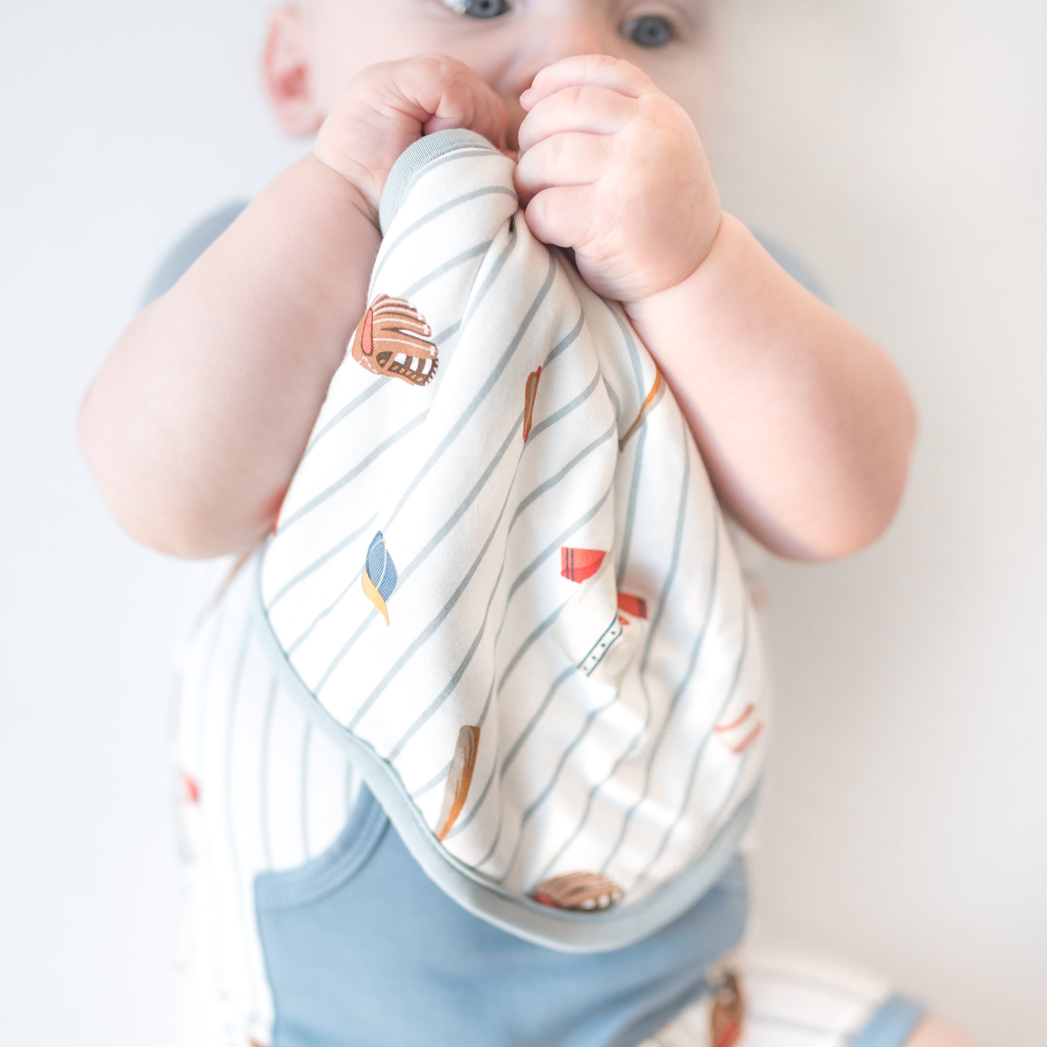 Infant holding the Lovey in Home Run with Removable Wooden Teething Ring