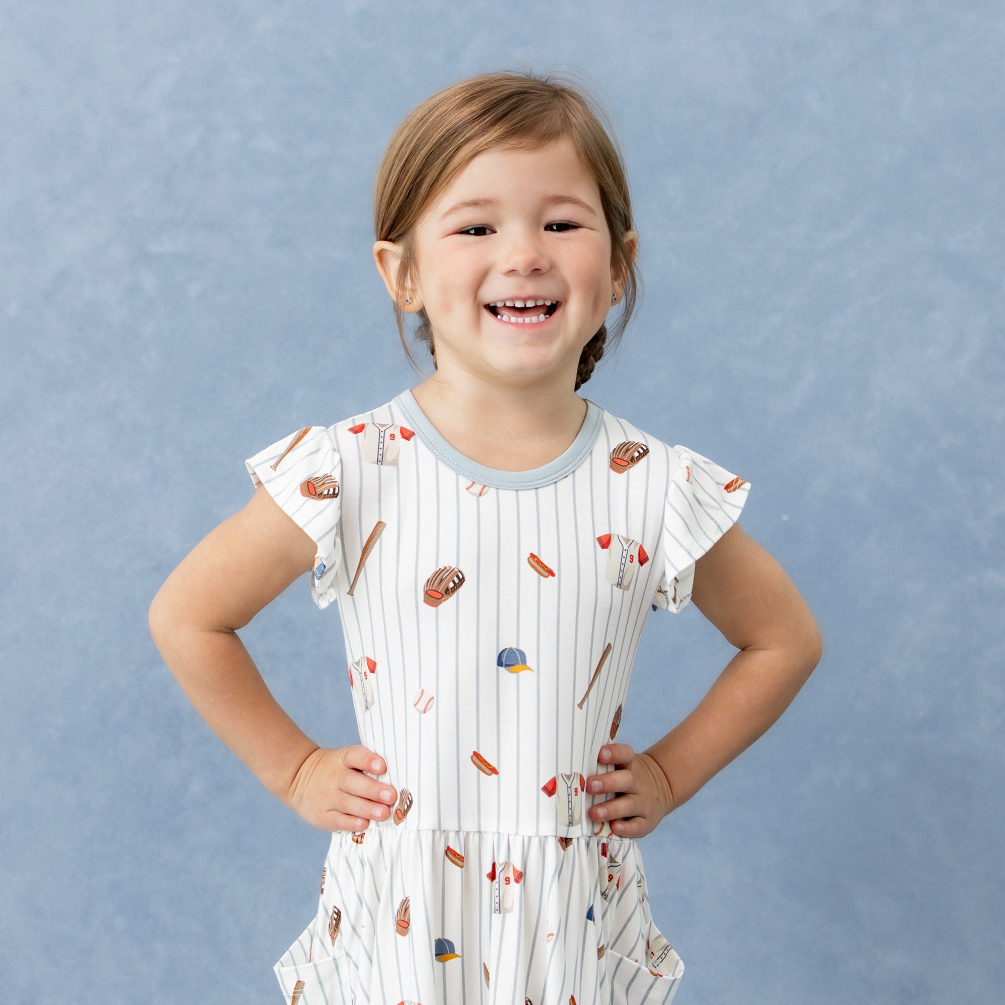 Close up of the top part of the Pocket Dress in Home Run with flutter sleeves shown on a young girl model