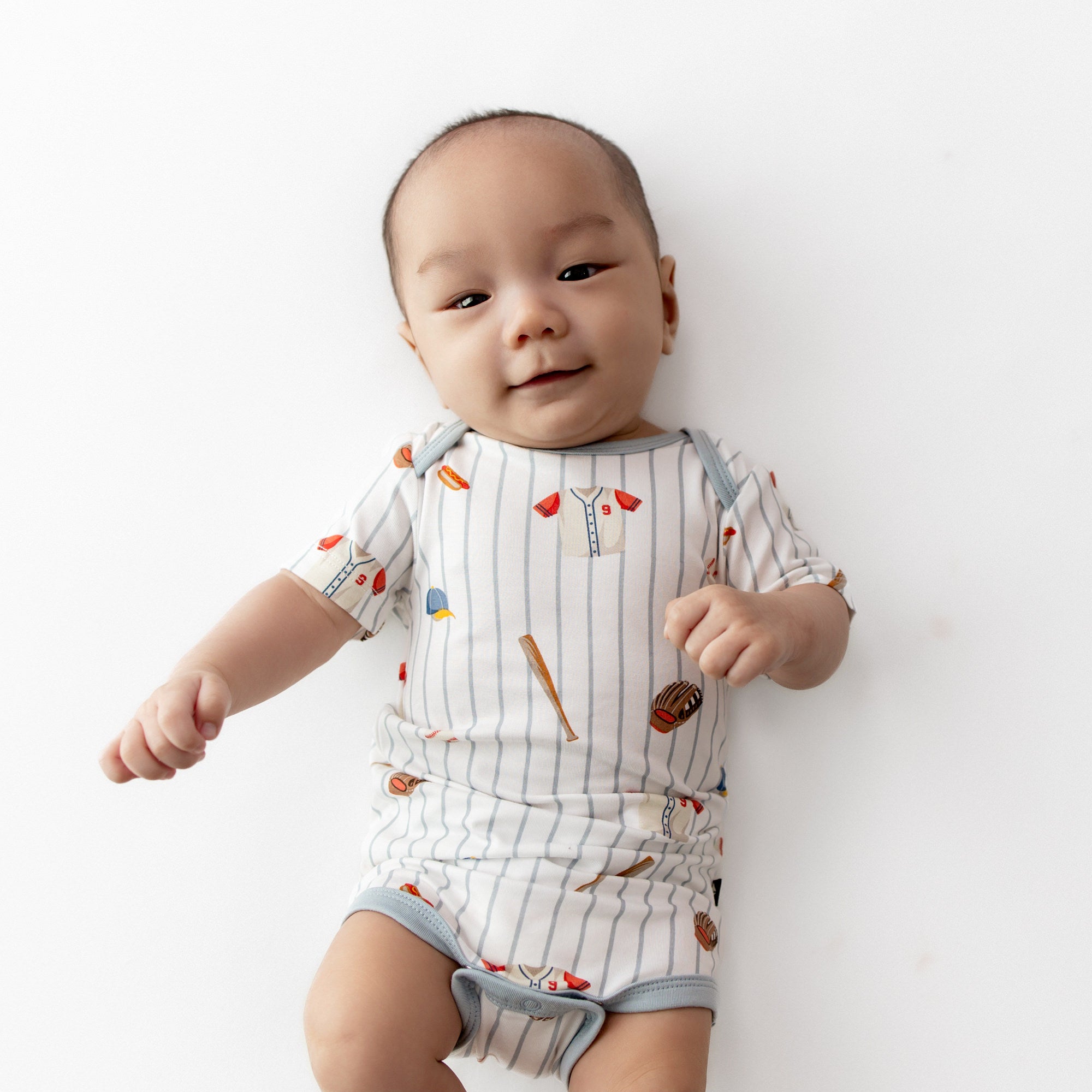 Infant laying on a white surface wearing the Bodysuit in Home Run