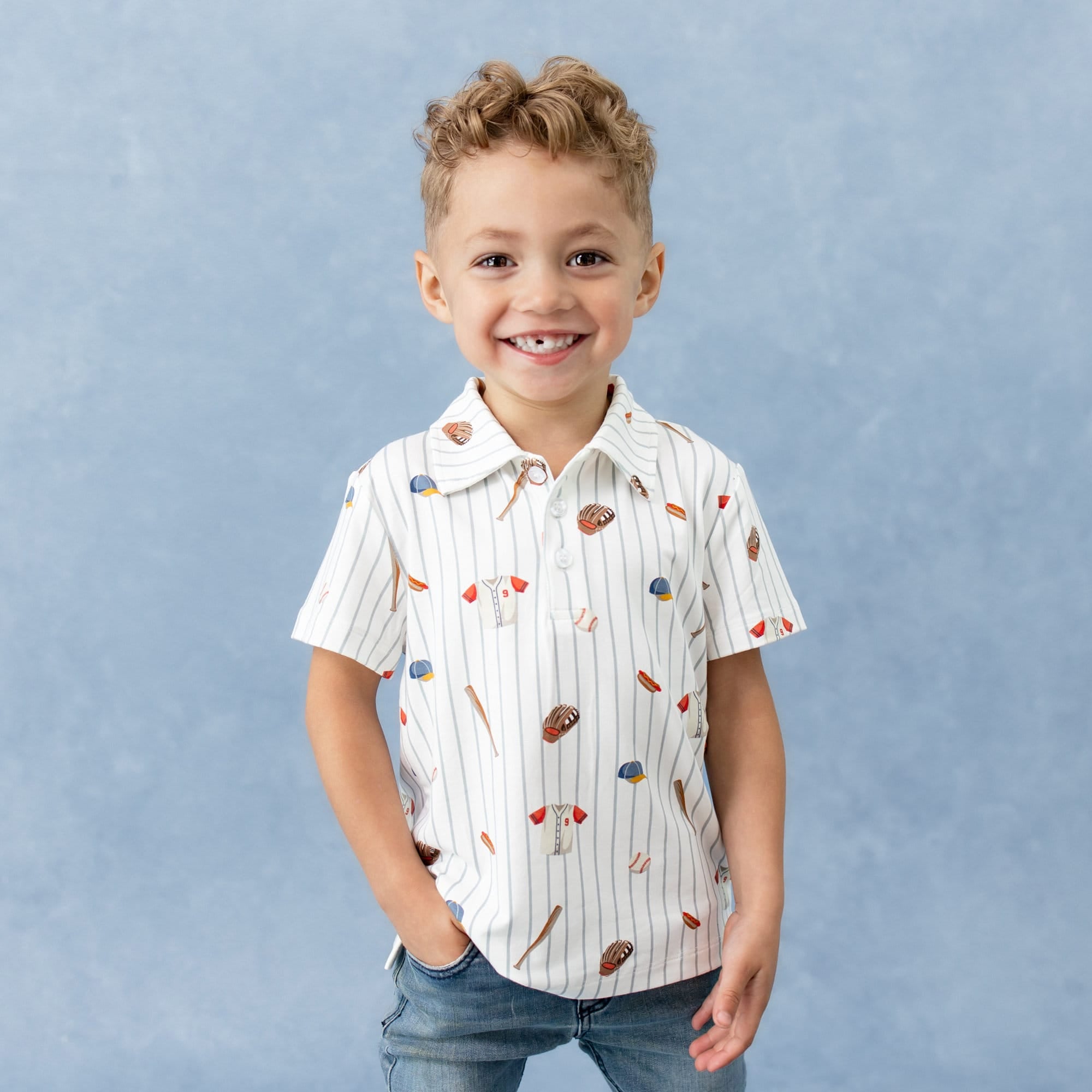 Young smiling boy wearing the Toddler Short Sleeve Polo in Home Run with one hand in his jeans pocket