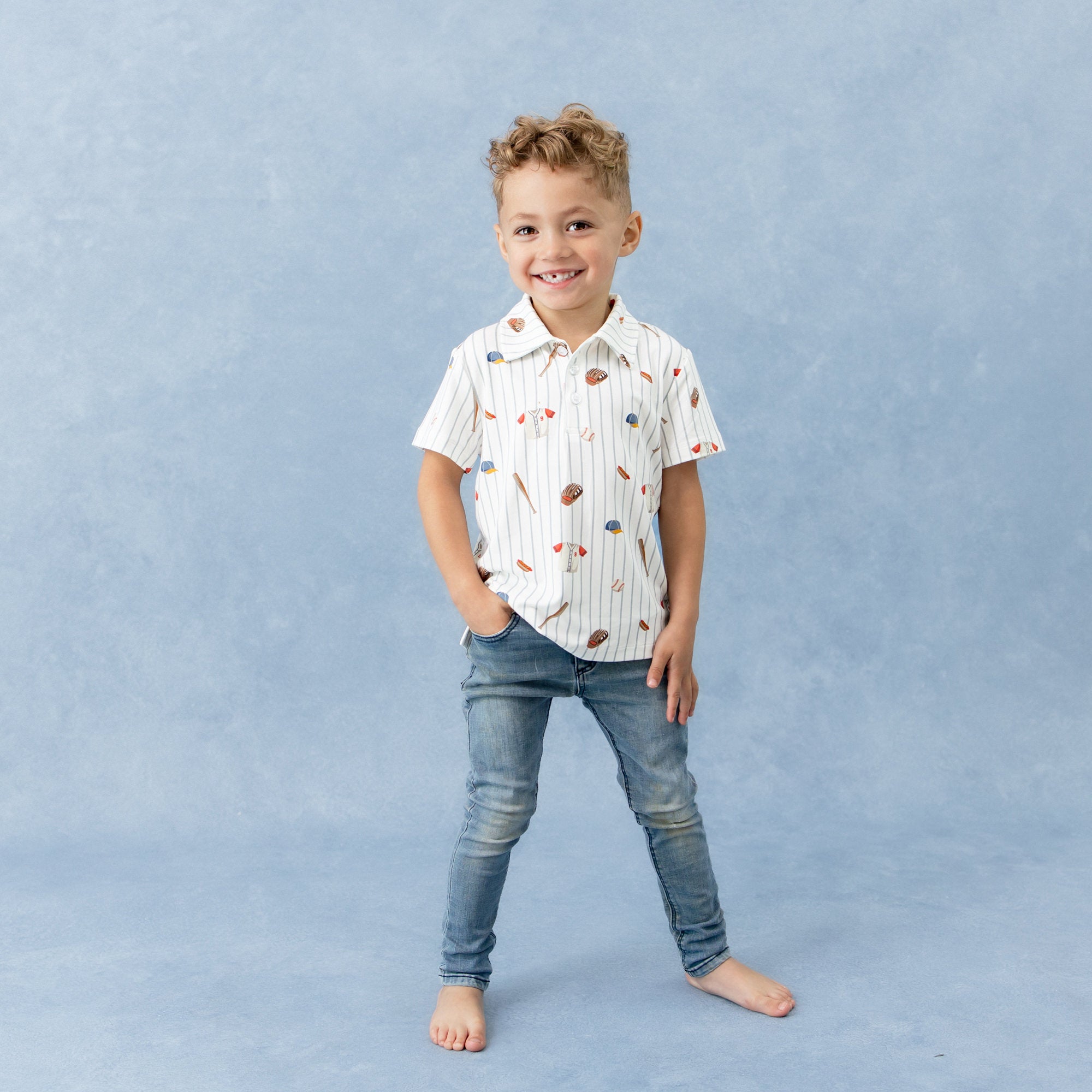 Young boy posing wearing the Toddler Short Sleeve Polo in Home Run and medium wash jeans