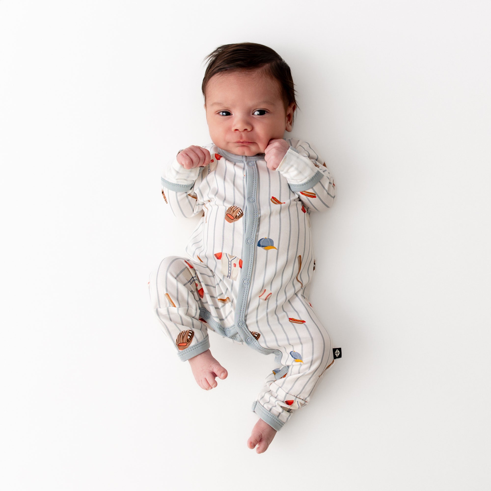 Newborn laying on a white surface wearing the Romper in Home Run