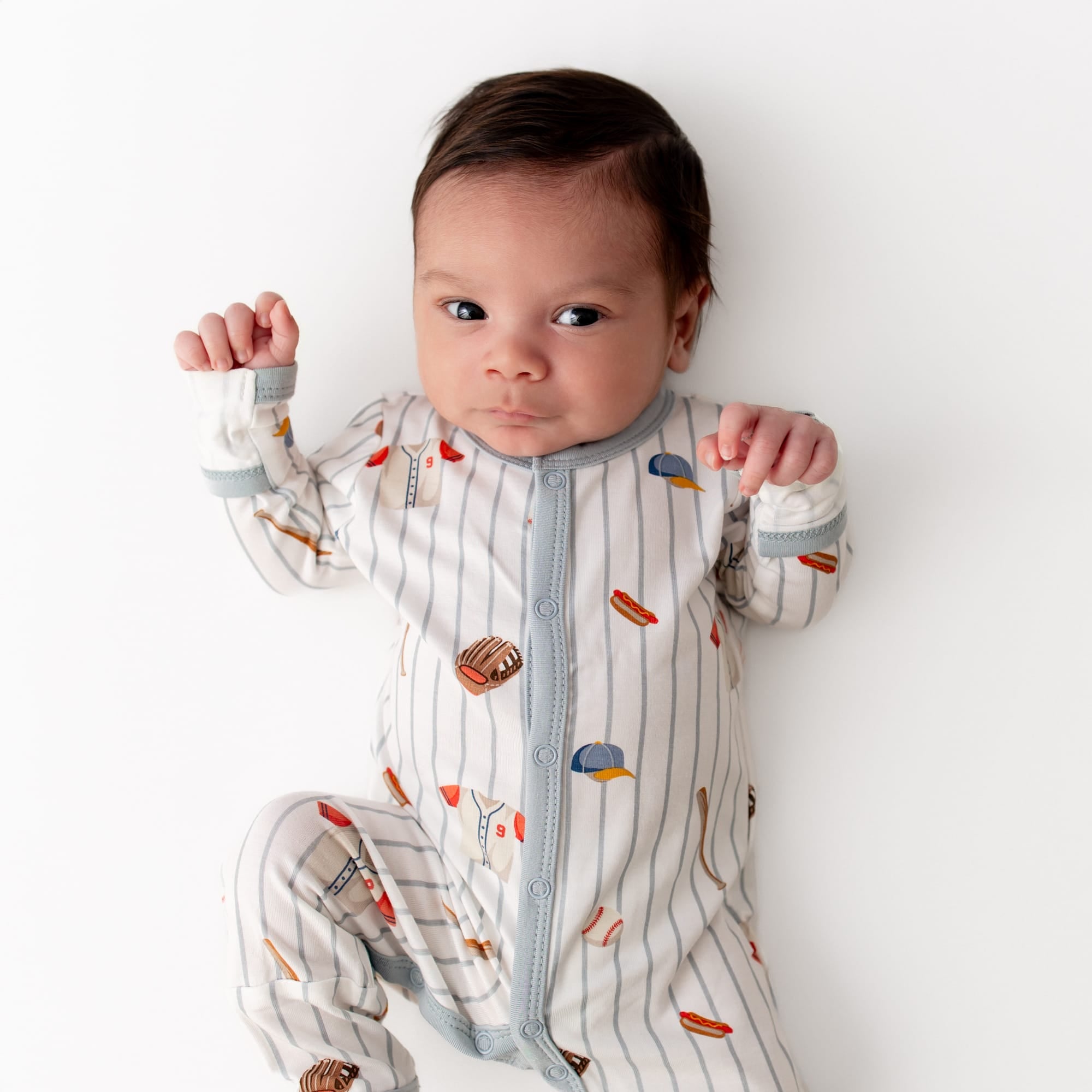 Close up of newborn wearing the Romper in Home Run on a white surface