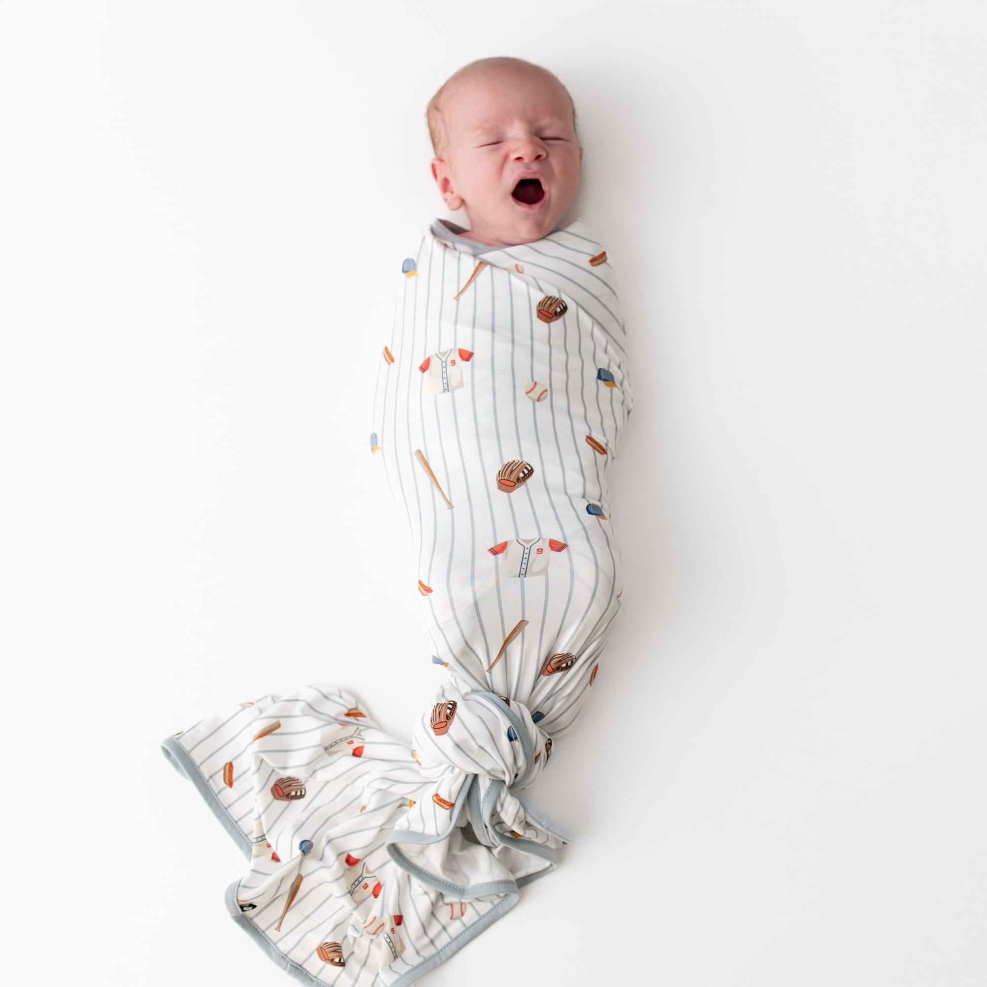 Yawning newborn swaddled in the Swaddle Blanket in Home Run